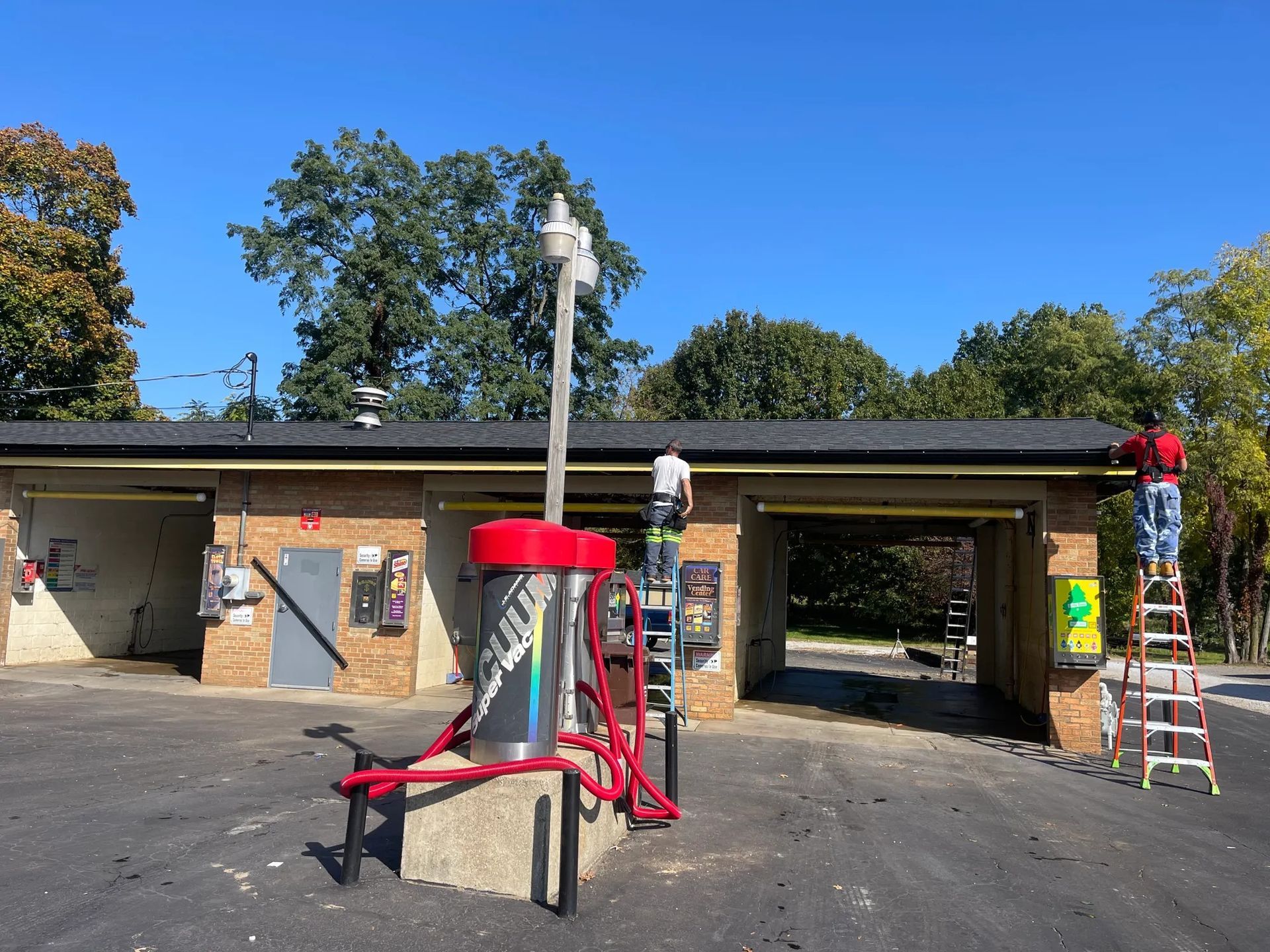 Old gas station pumps with red tops in a parking lot under a blue sky
