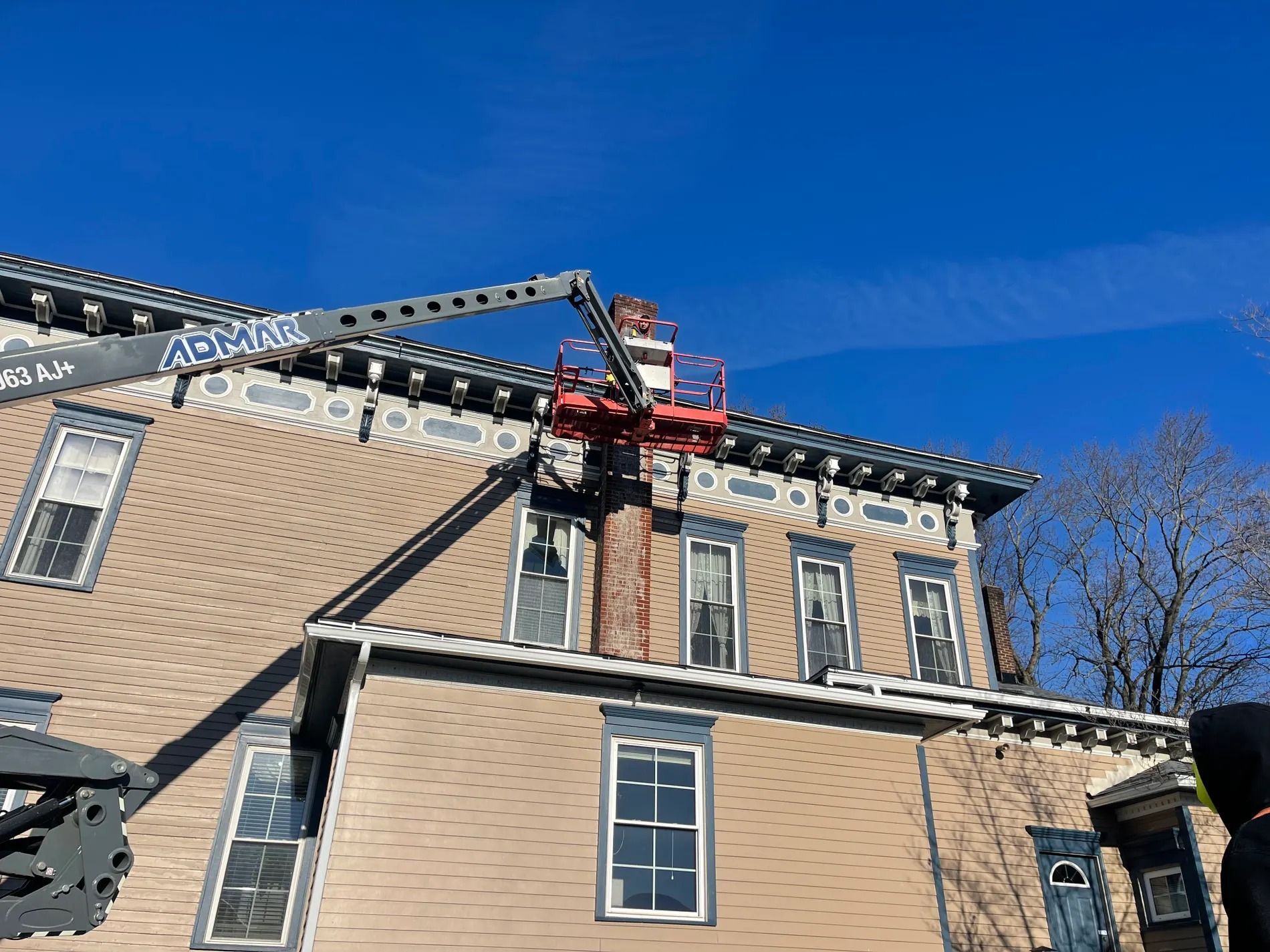 Fire truck ladder extended to a brick building roof under a clear blue sky