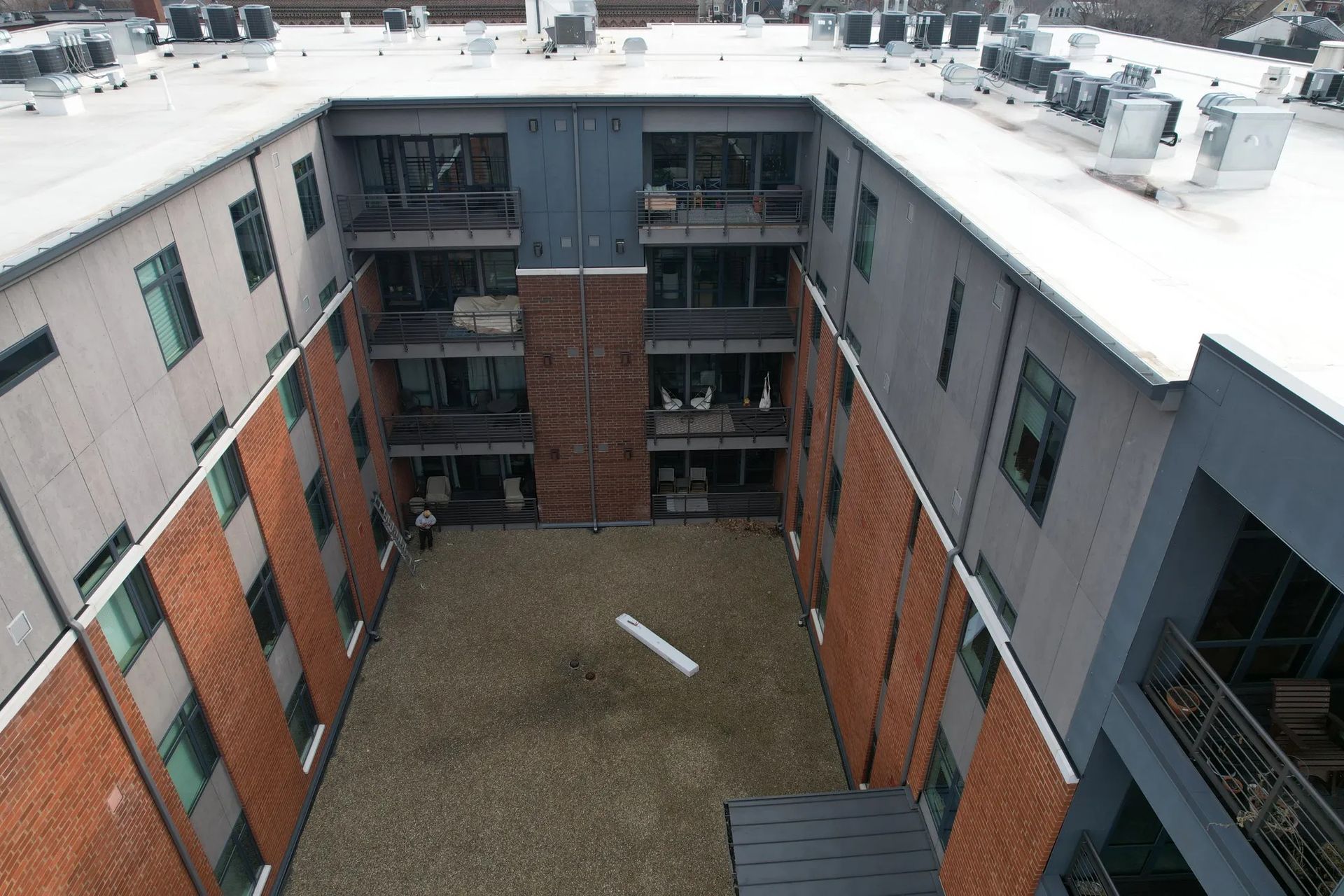 Snow-covered apartment courtyard with brick and gray buildings surrounding a central open area