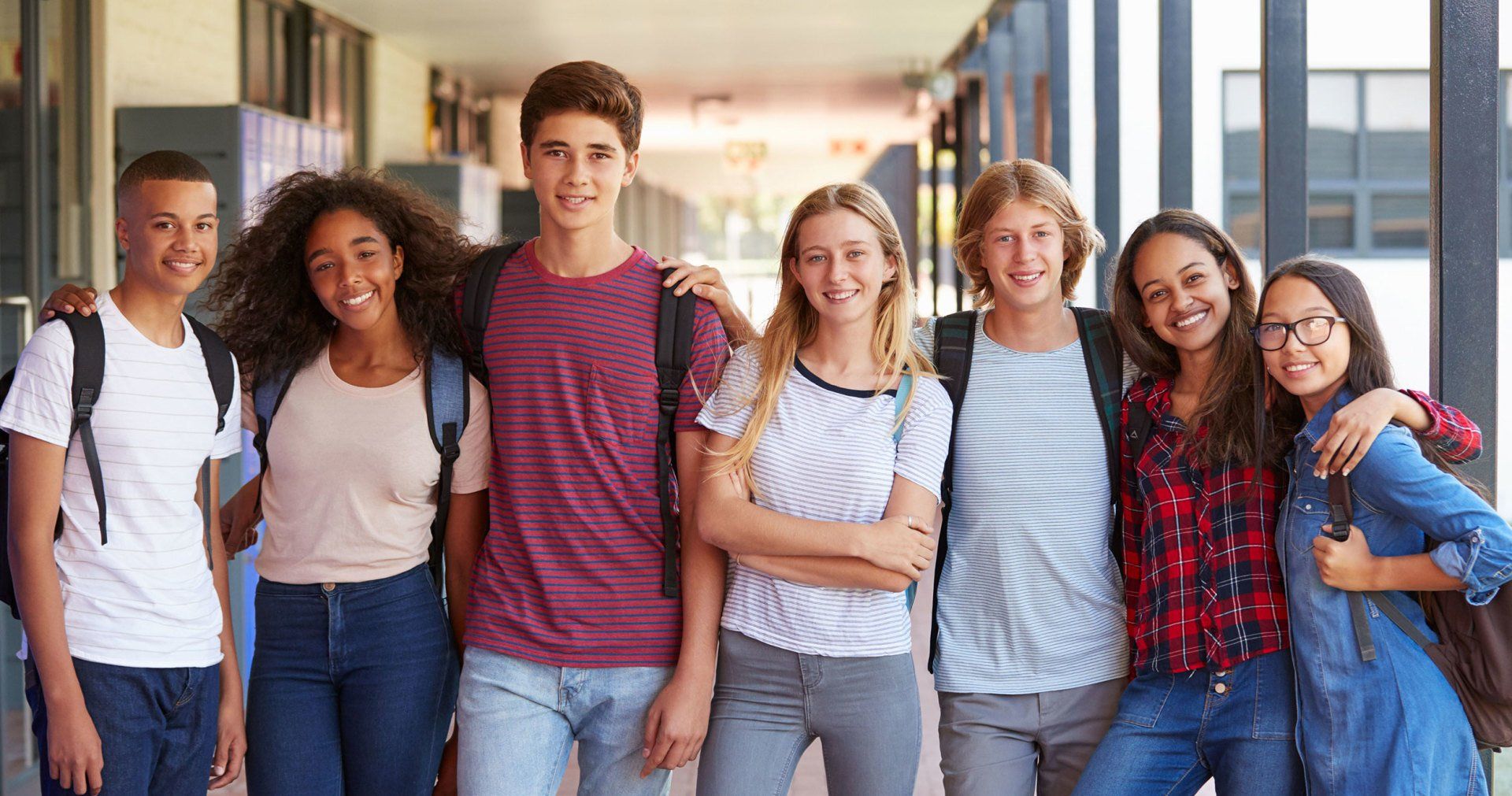 A group of young people are posing for a picture in a hallway.