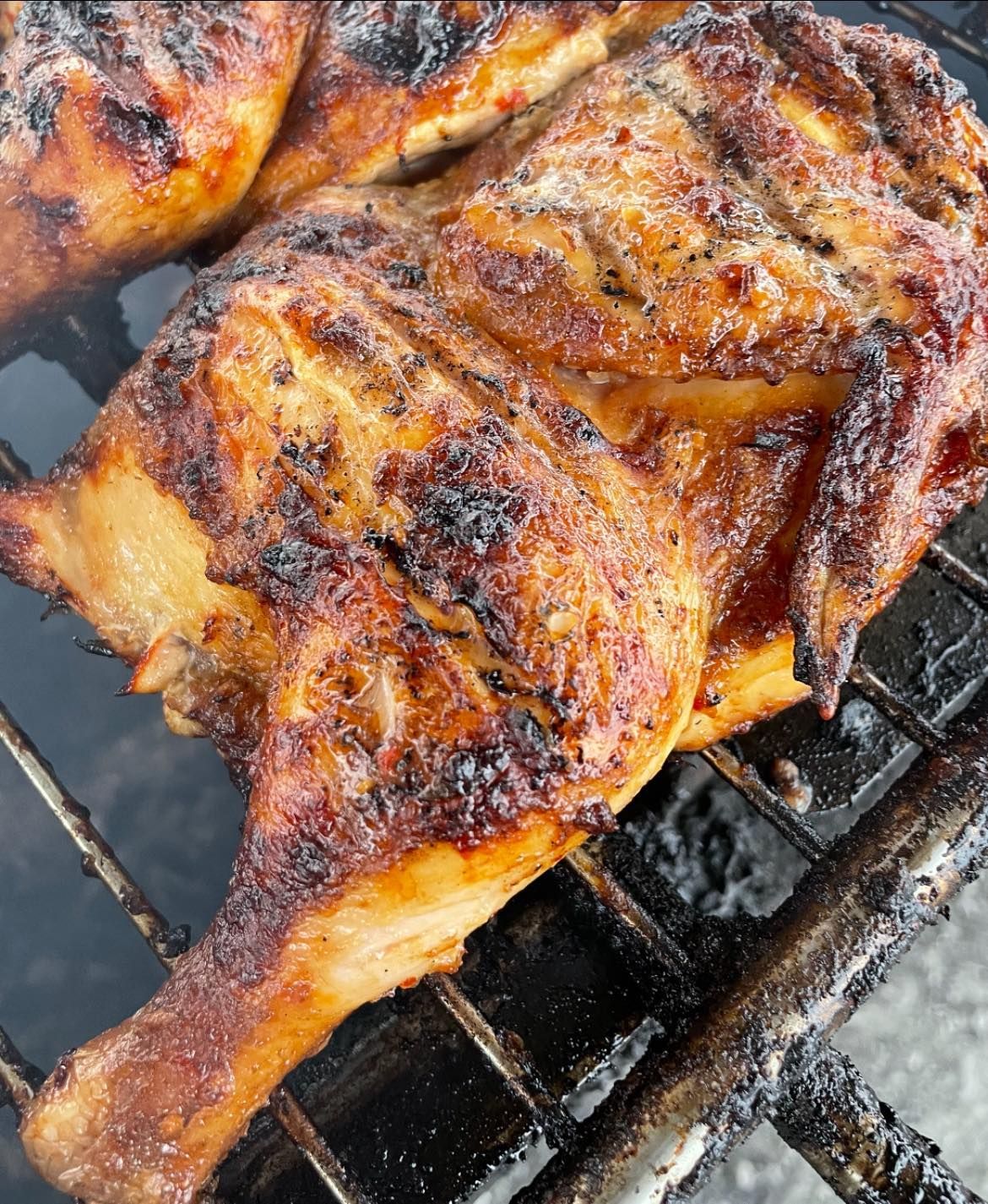Two pieces of chicken are cooking on a grill