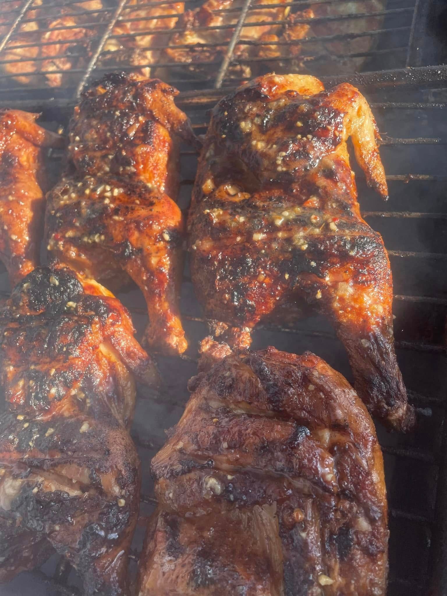 Chicken is being cooked on a grill with smoke coming out of it.