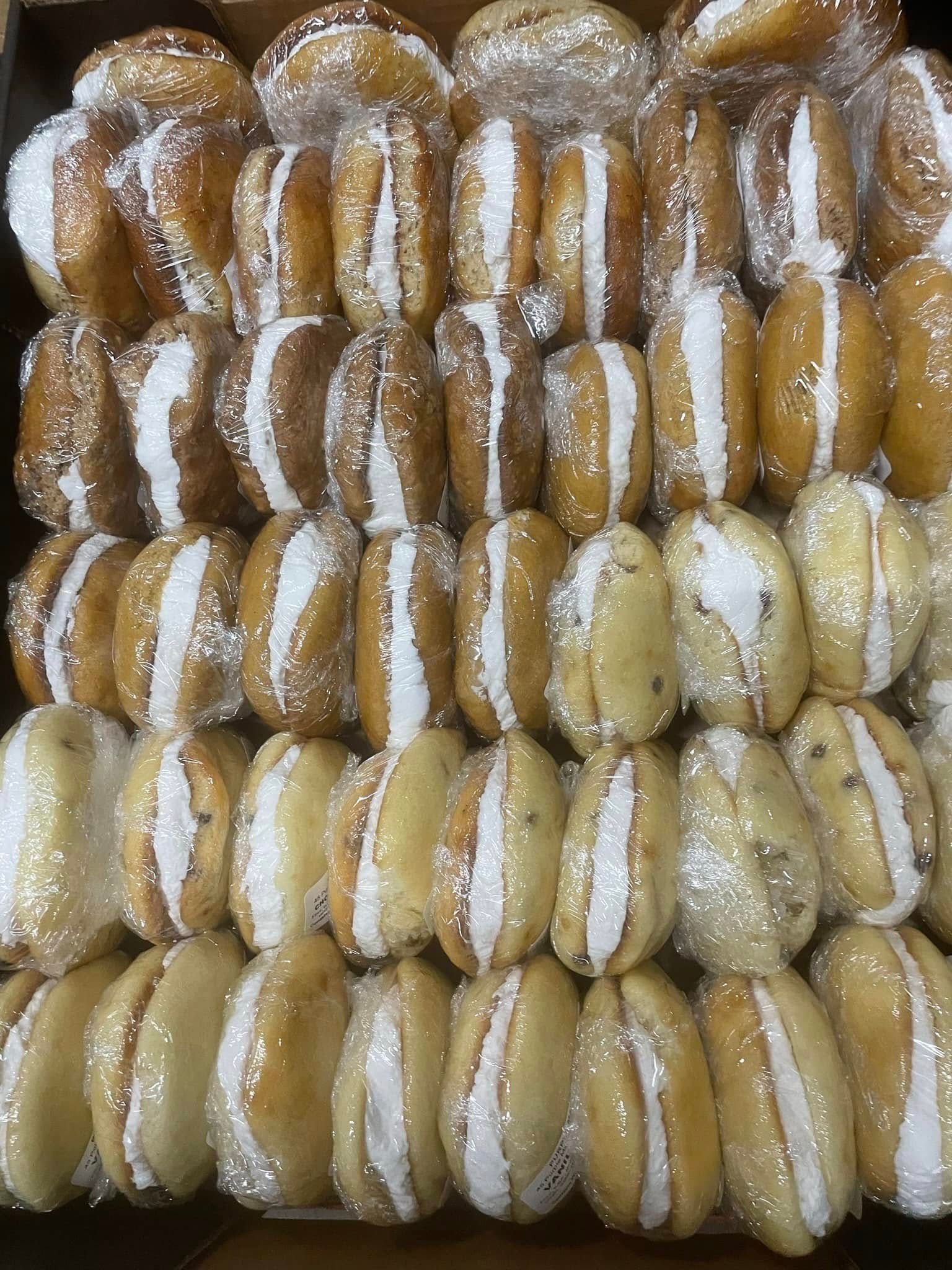 A box filled with a variety of cookies and donuts covered in powdered sugar.