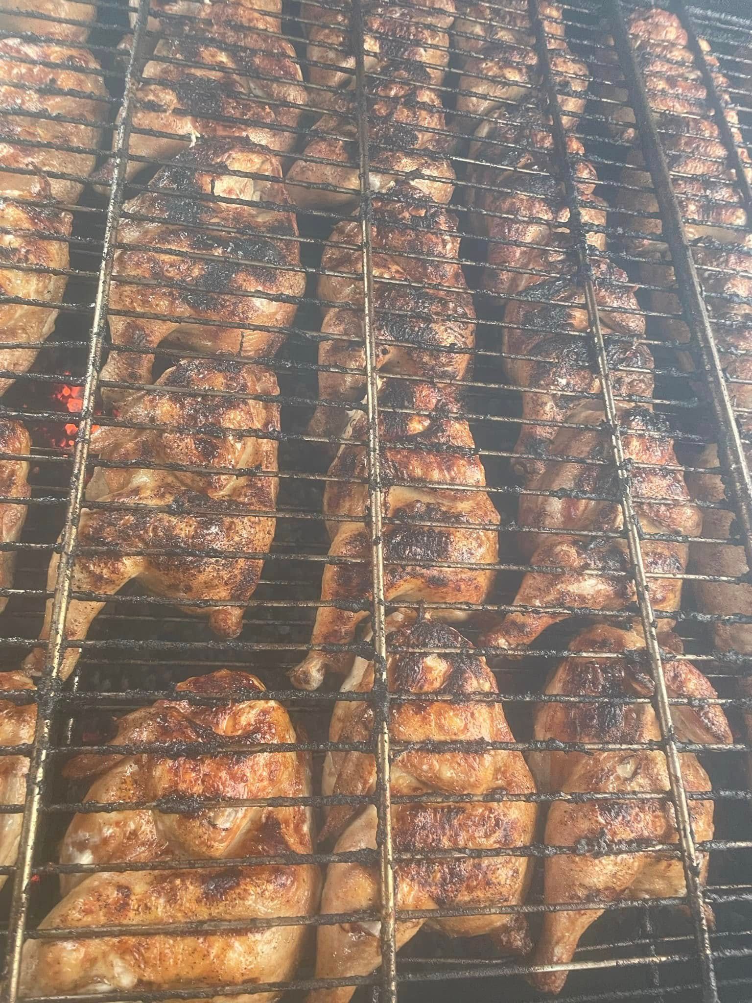 A bunch of chicken wings are cooking on a grill.