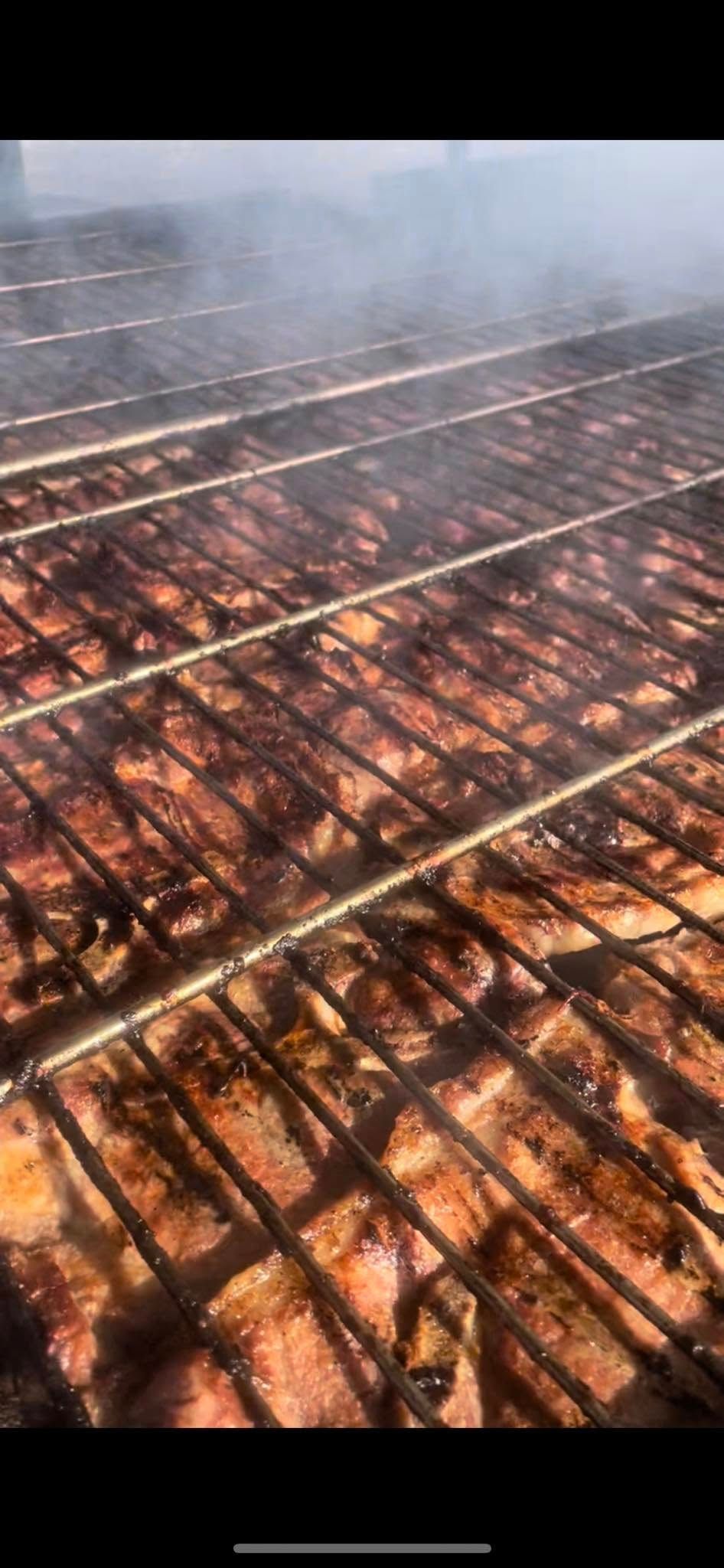 A large amount of meat is being cooked on a grill.