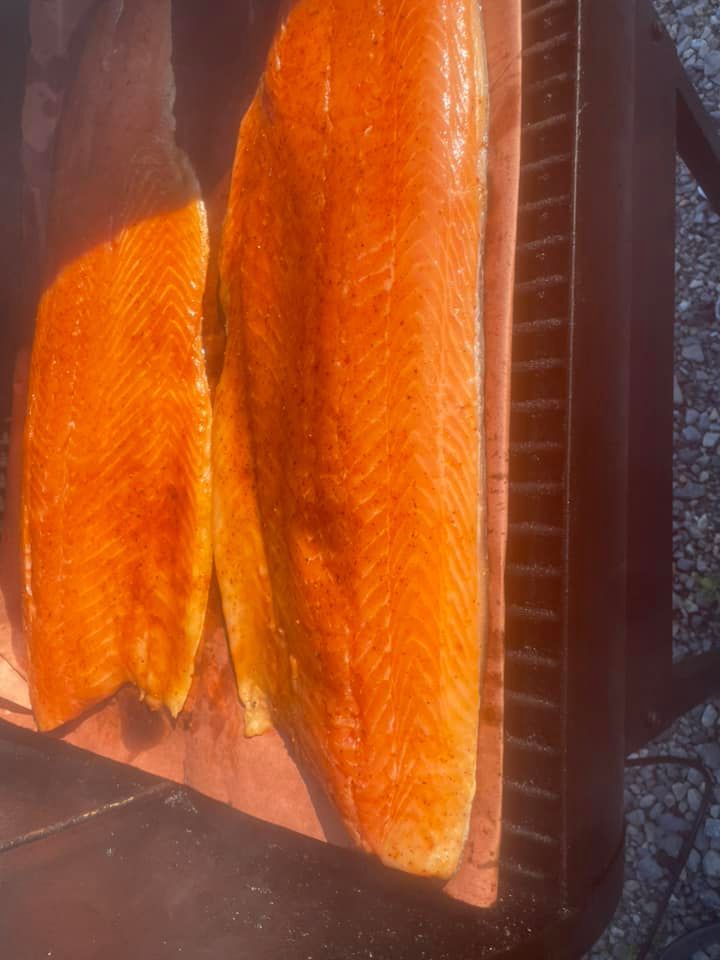 Two pieces of salmon are being smoked on a grill.