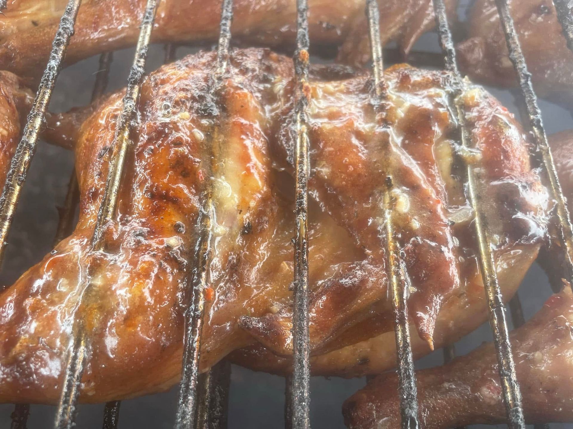 A chicken is cooking on a grill with smoke coming out of it.