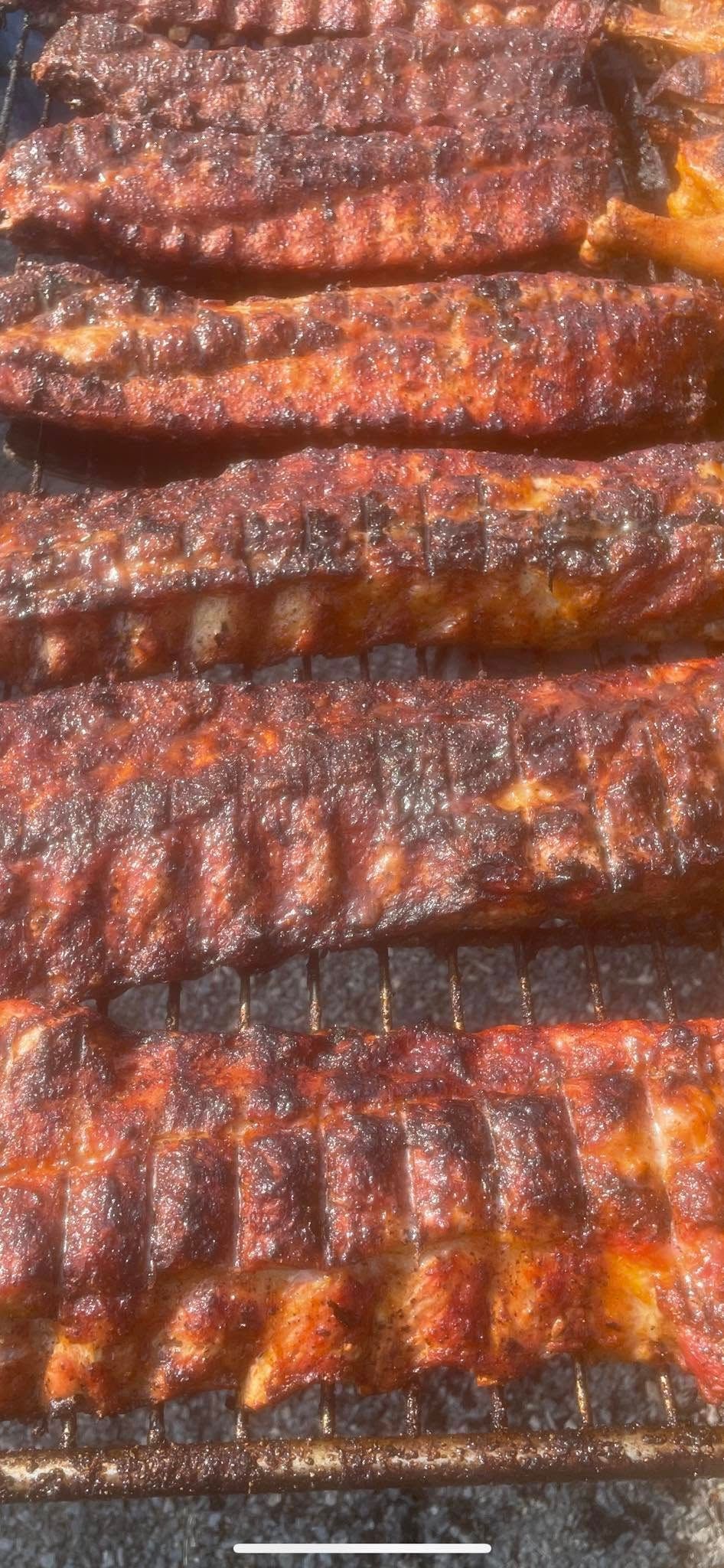 A close up of ribs cooking on a grill.