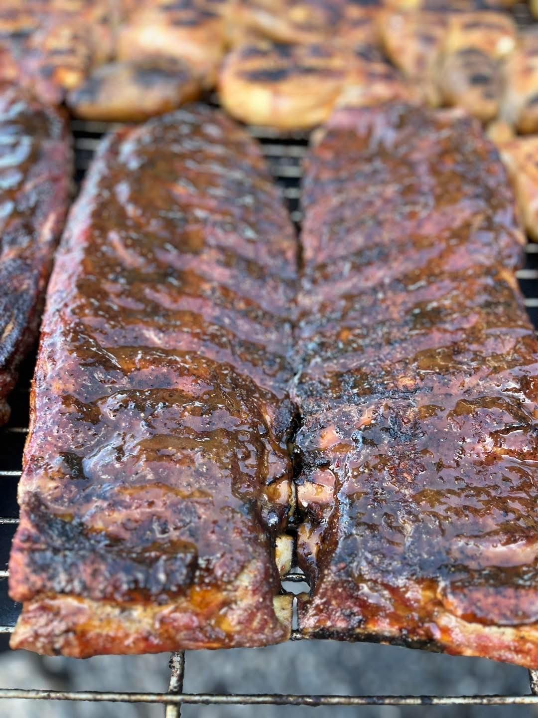 A close up of ribs cooking on a grill.