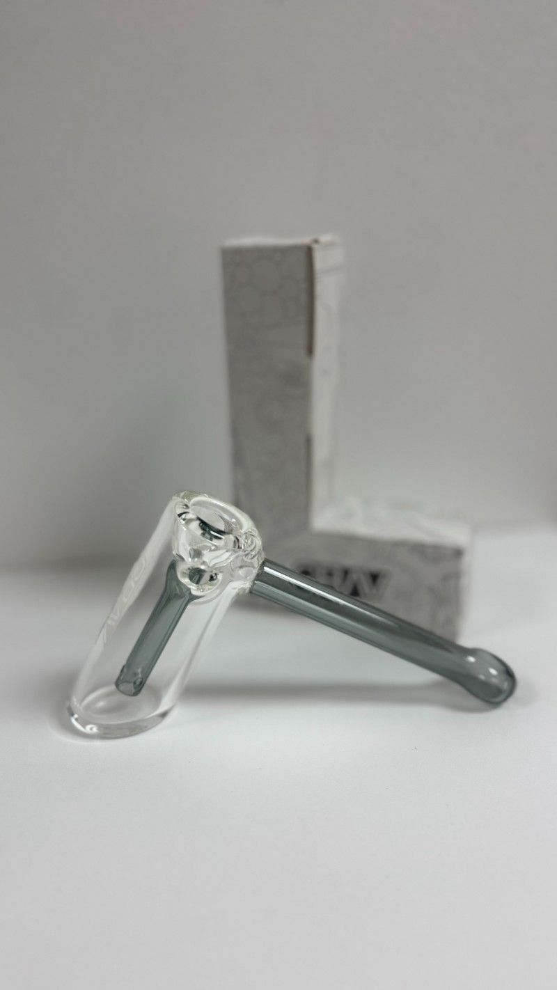 A glass pipe is sitting on a white table next to a box.