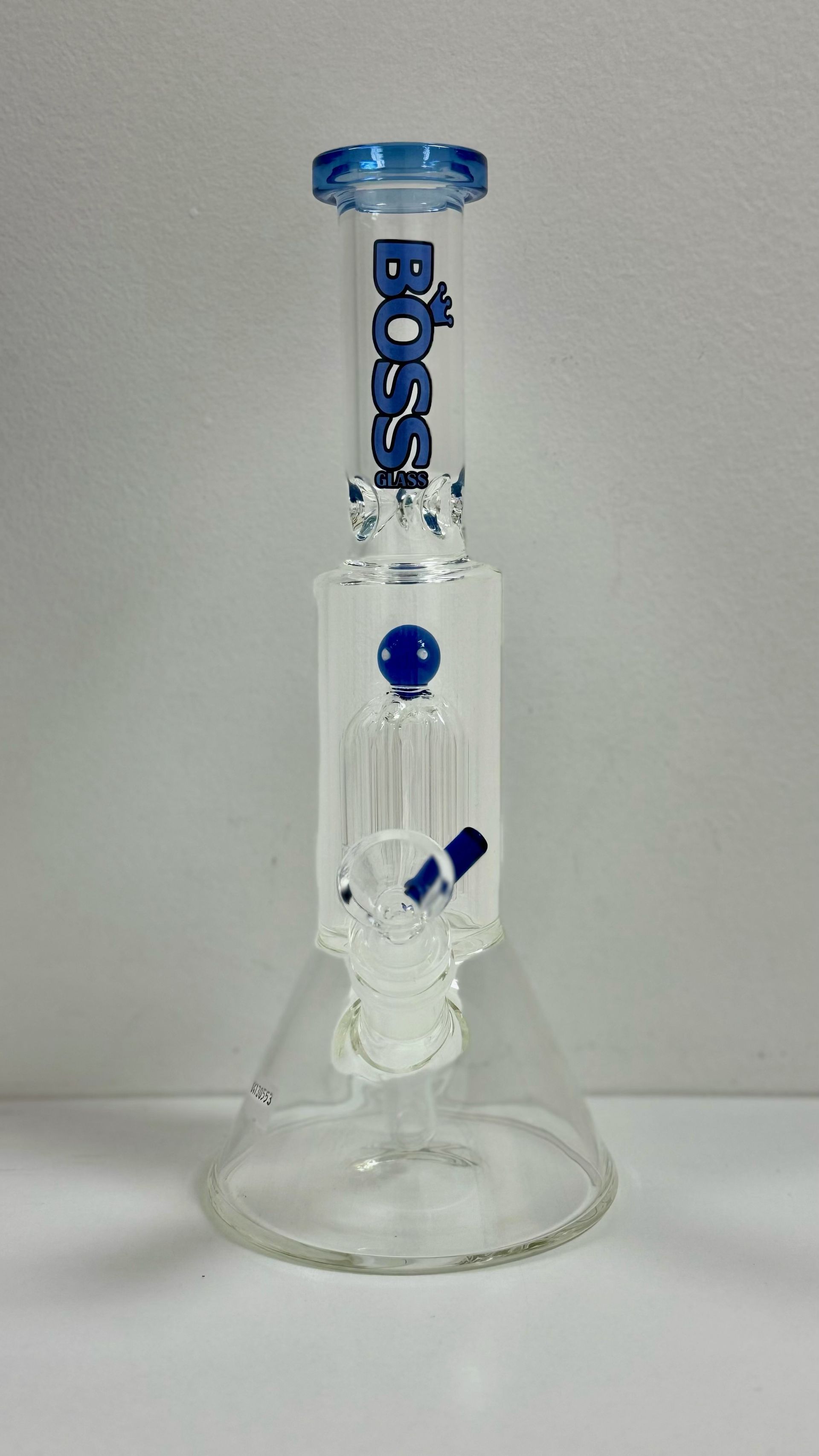 A glass bong with a blue top is sitting on a white table.