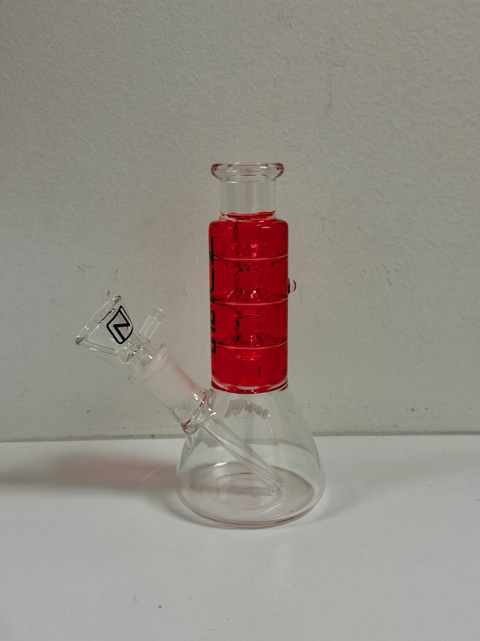 A clear glass bong with a red stripe on the top