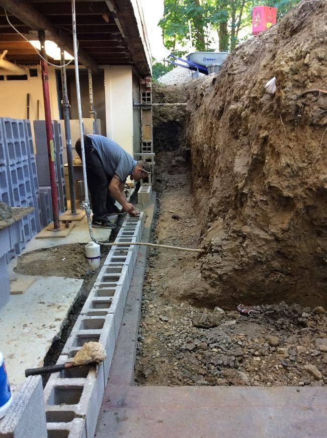 A man is working on a concrete block wall
