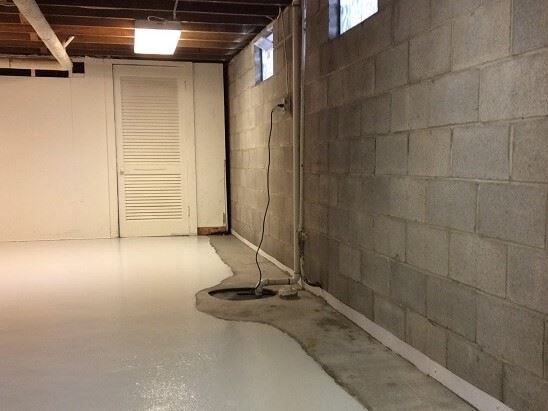 A basement with a white floor and brick walls.
