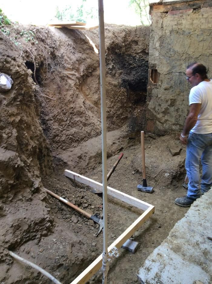 A man is standing in the dirt looking at a hole in the ground