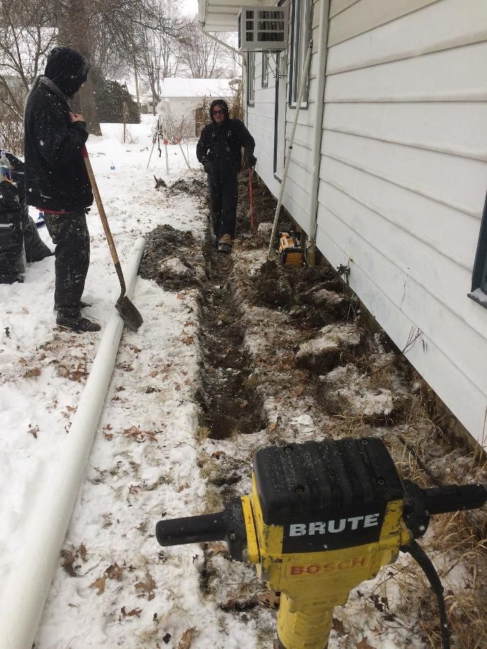 A brute hammer is sitting in front of a house in the snow.