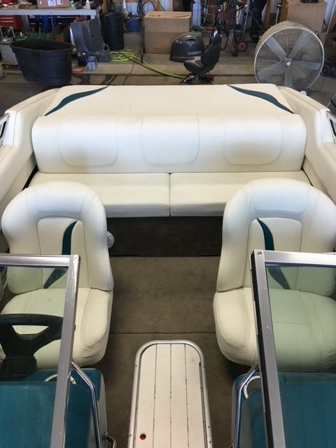 The inside of a boat with white and green seats.