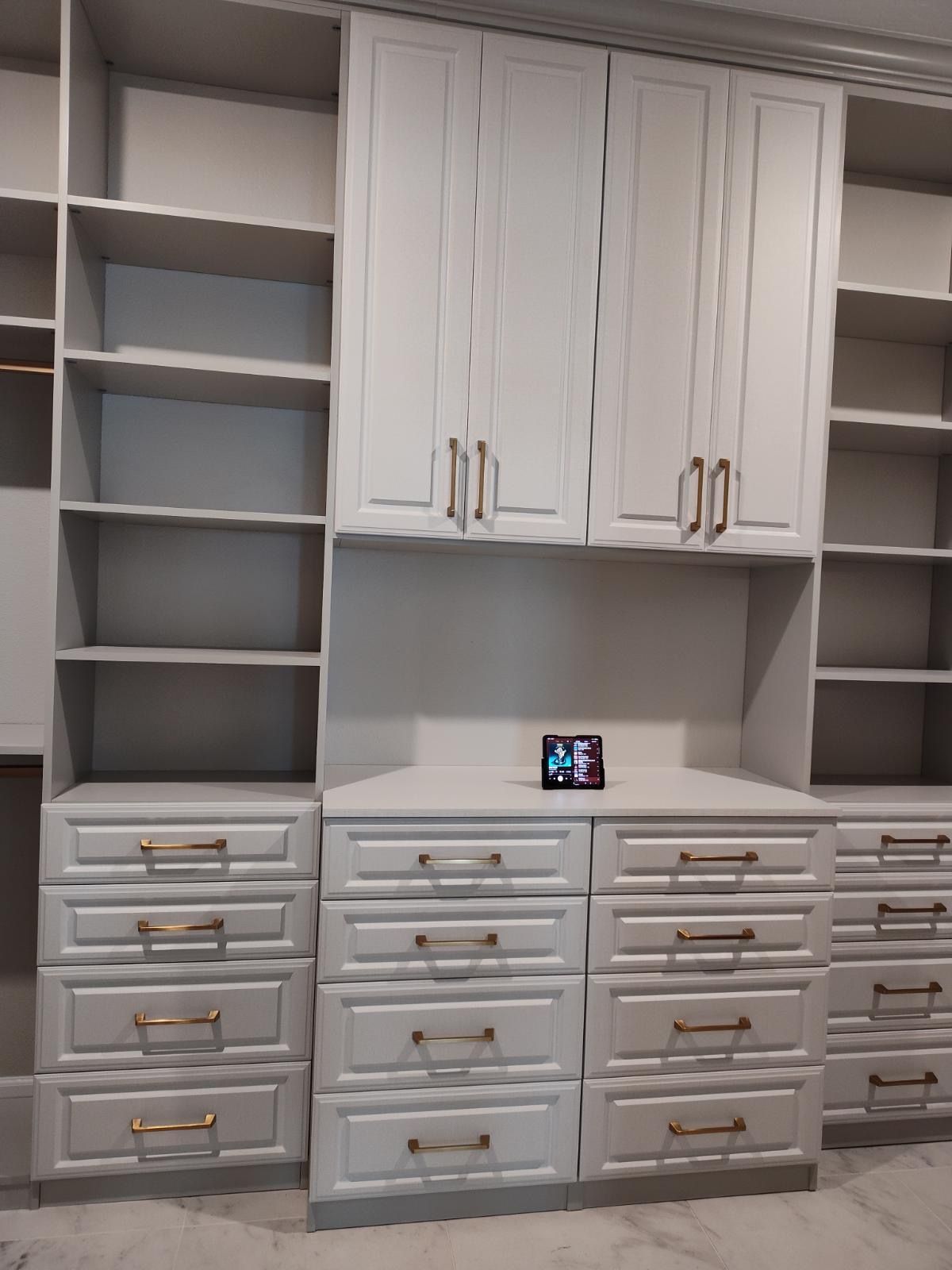 A room with a lot of white cabinets and drawers