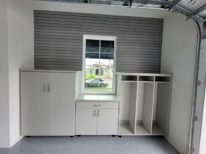 A room with white cabinets and a window with a car in the background.