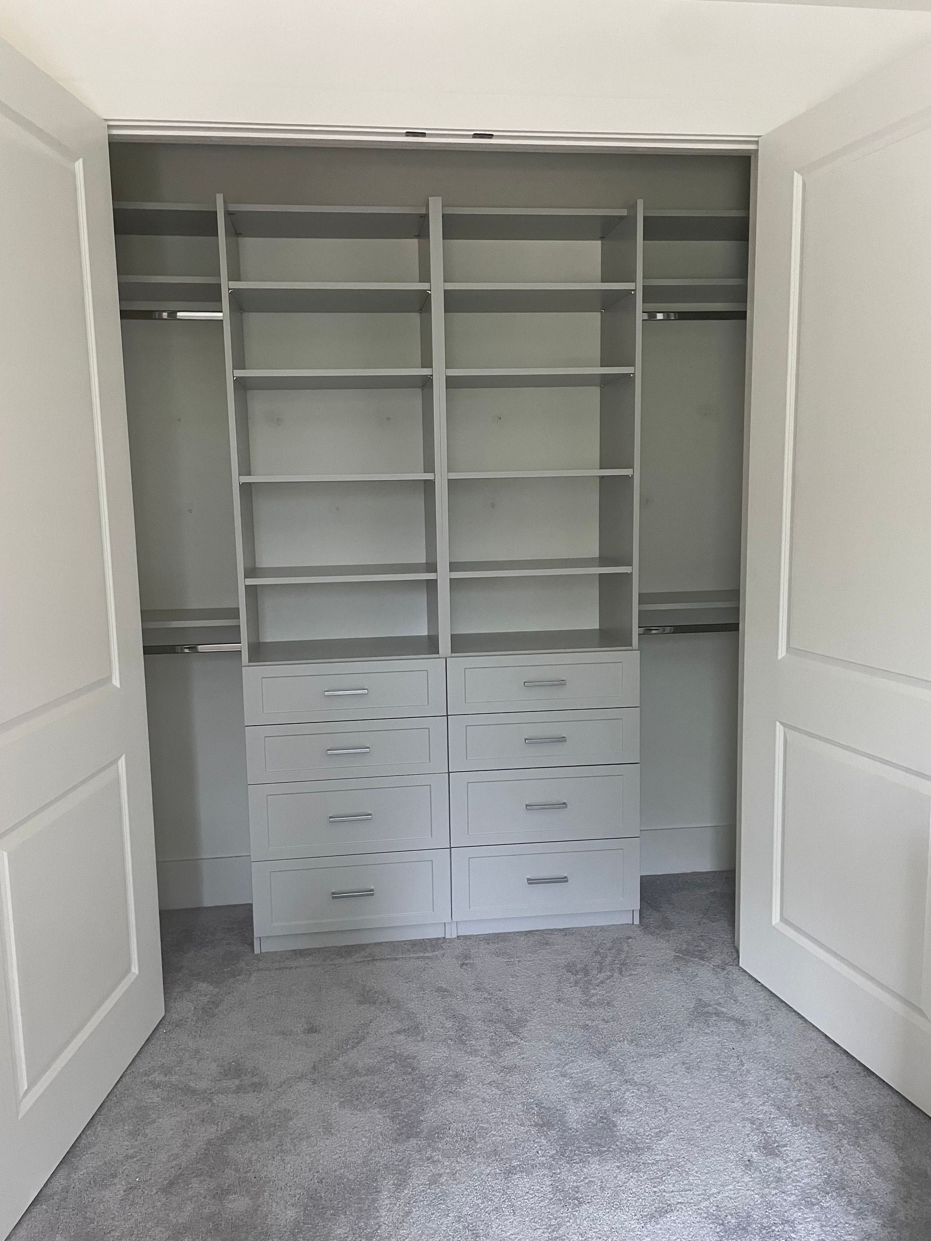 A walk in closet with lots of shelves and drawers