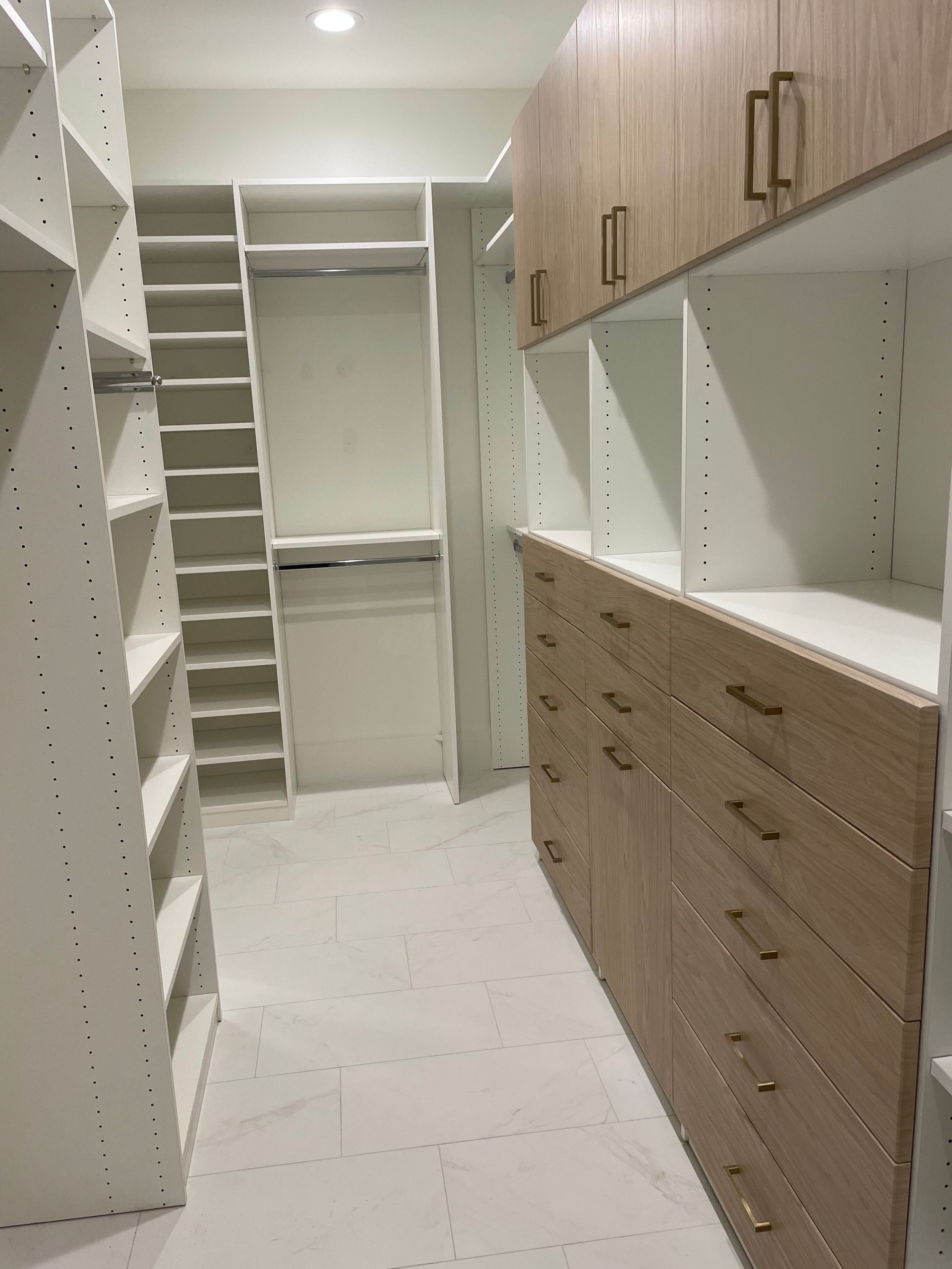 A walk in closet with lots of shelves and drawers