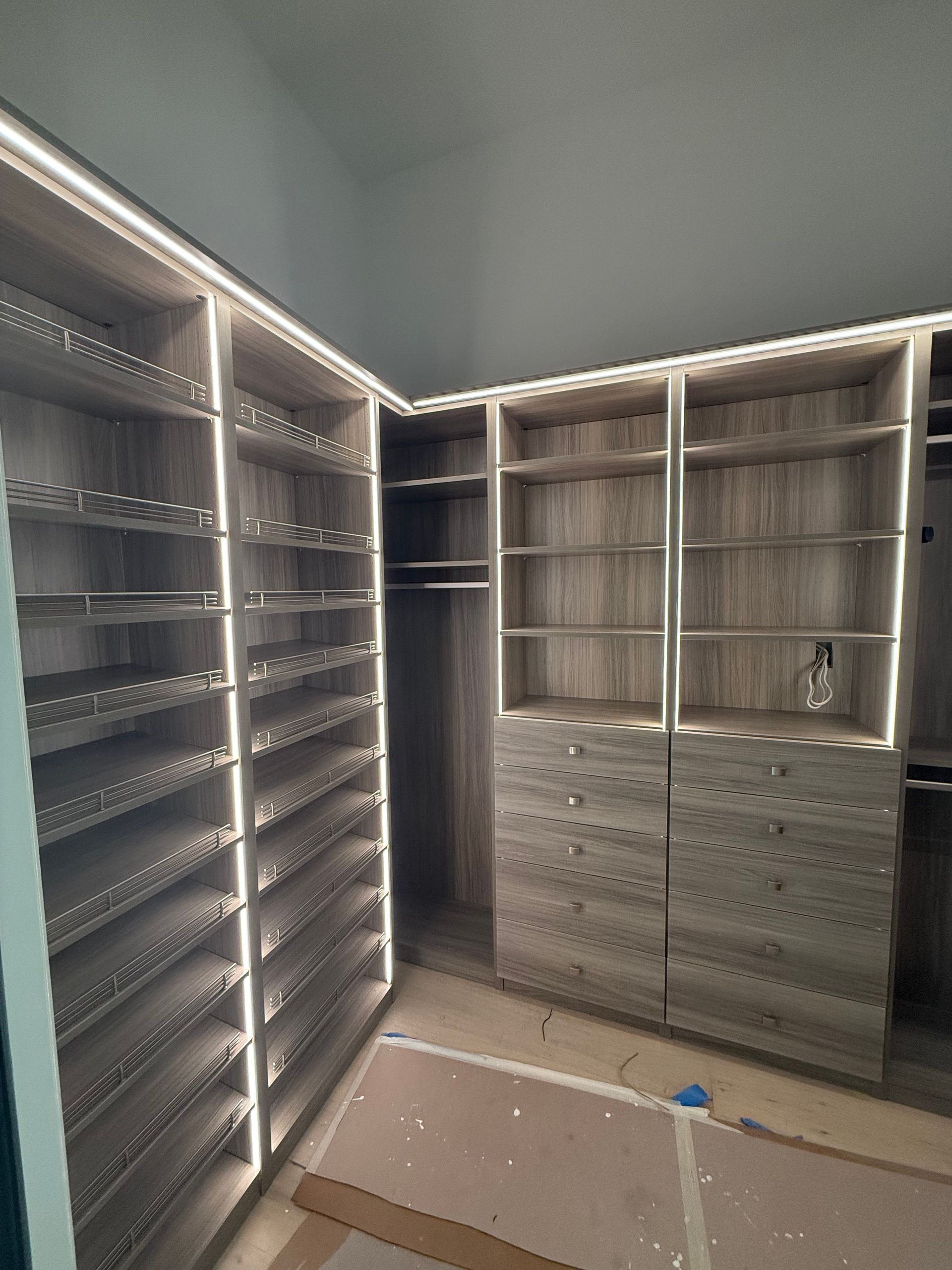 A walk in closet with lots of shelves and drawers.
