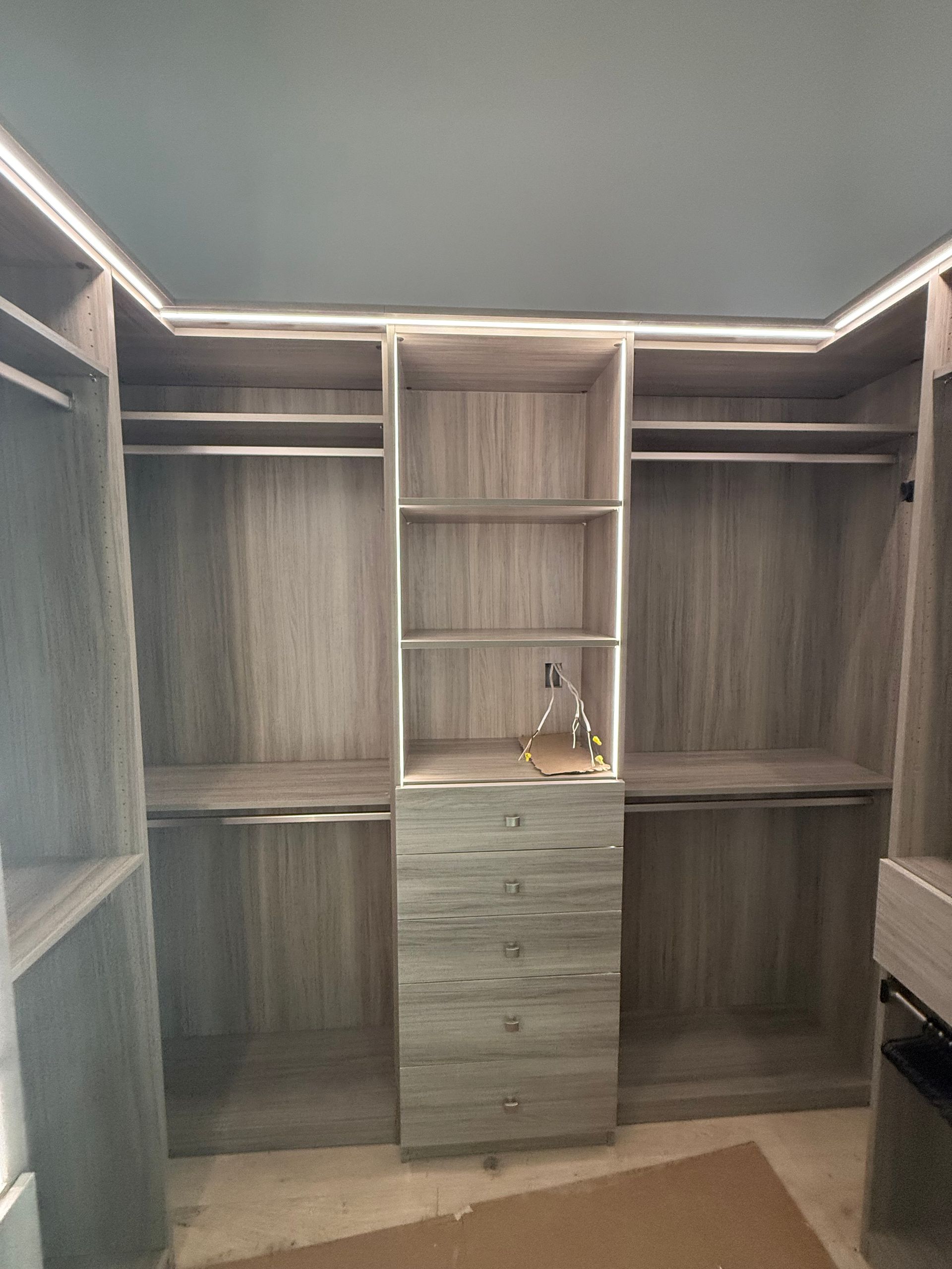 A walk in closet with lots of shelves and drawers.