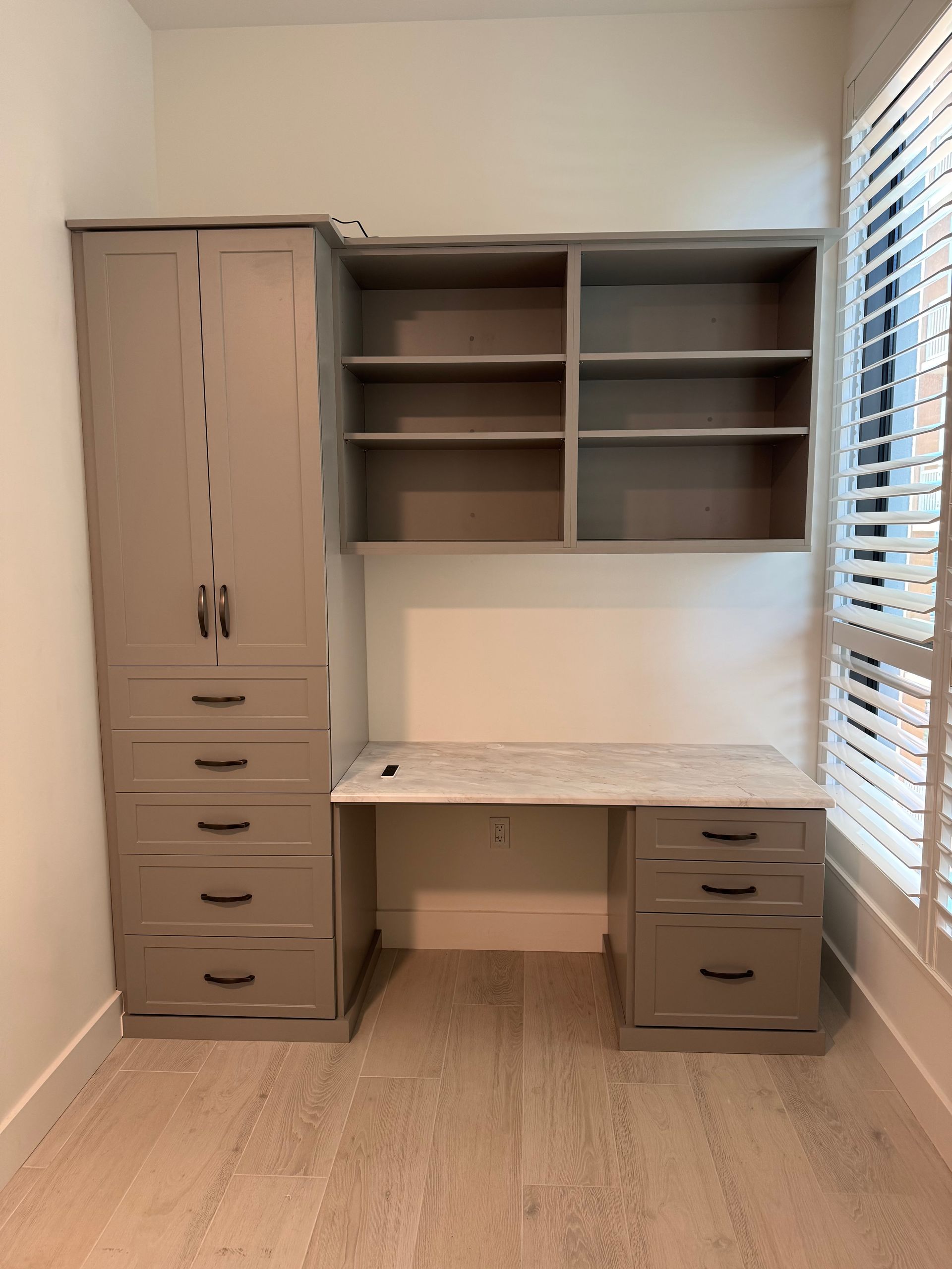 A room with a desk, shelves, drawers, and a window.