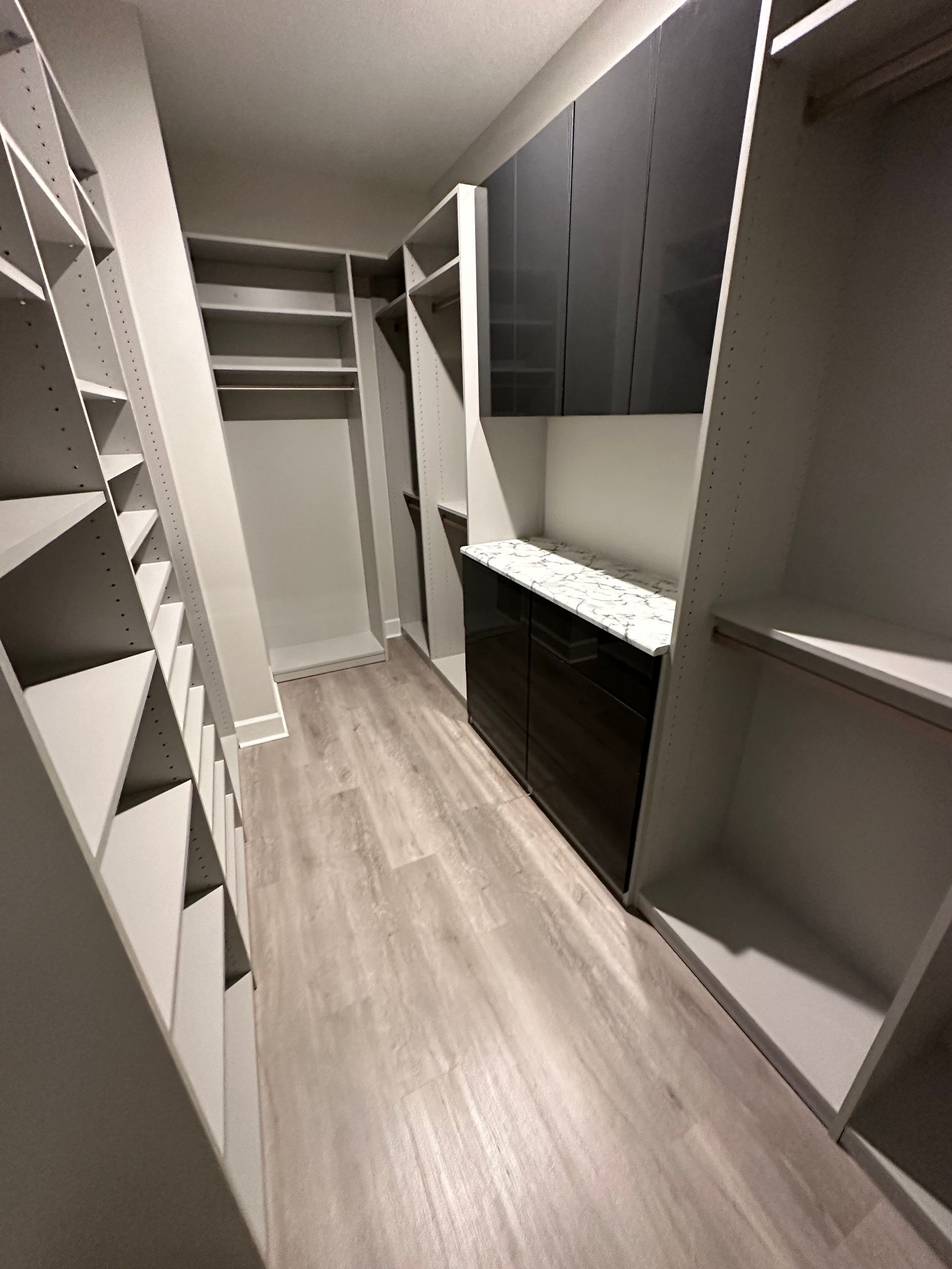 A walk in closet with lots of shelves and cabinets.