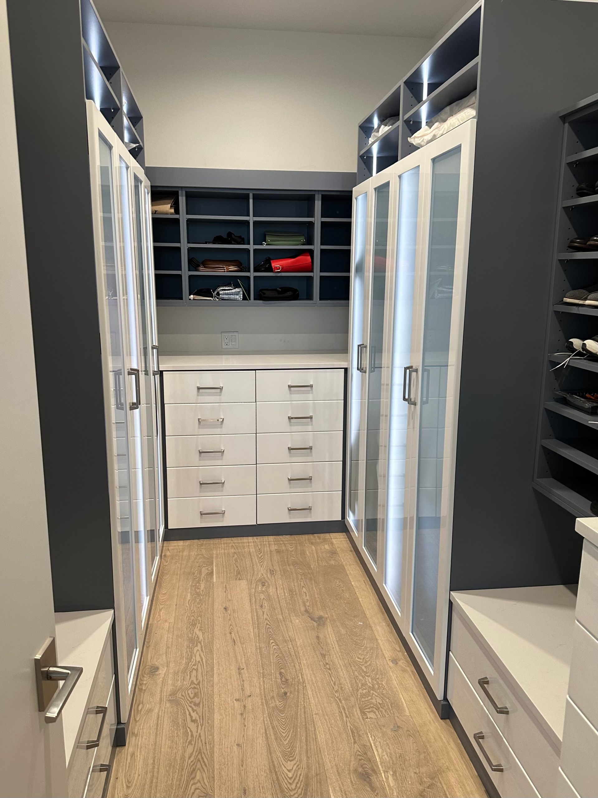 A walk in closet with lots of shelves and drawers.