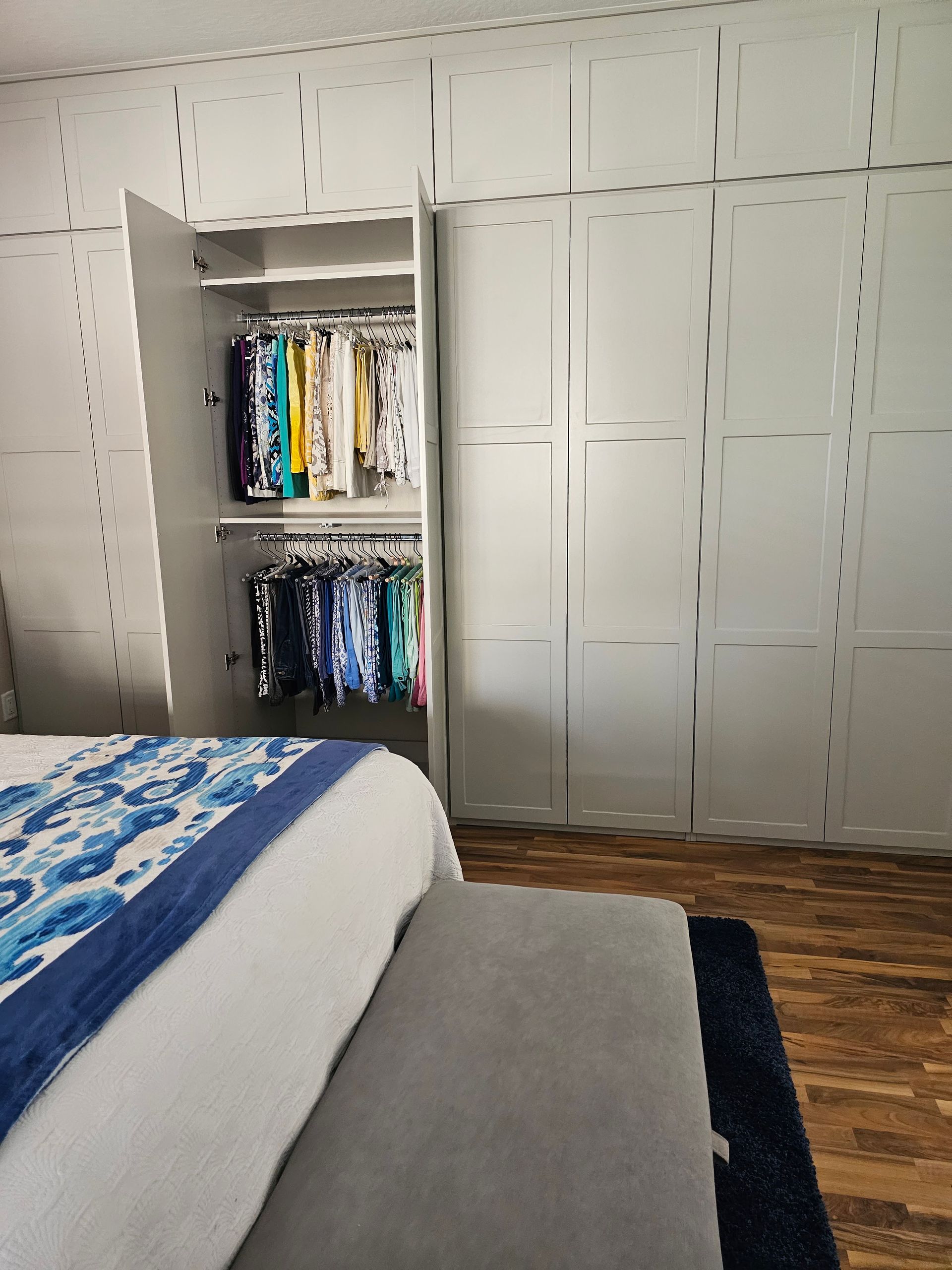 A bedroom with a bed and a closet filled with clothes
