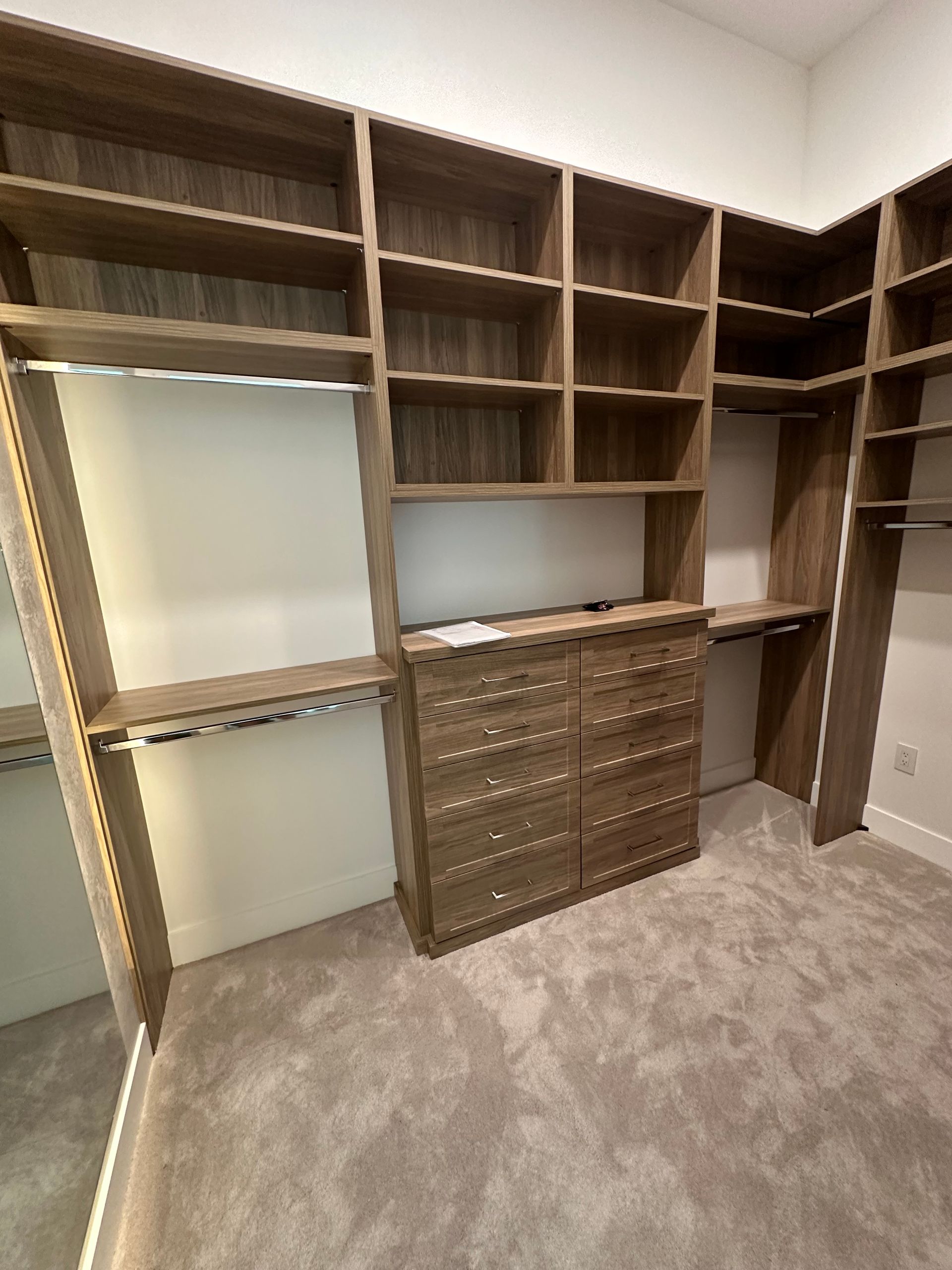 A walk in closet with lots of shelves and drawers and a mirror.