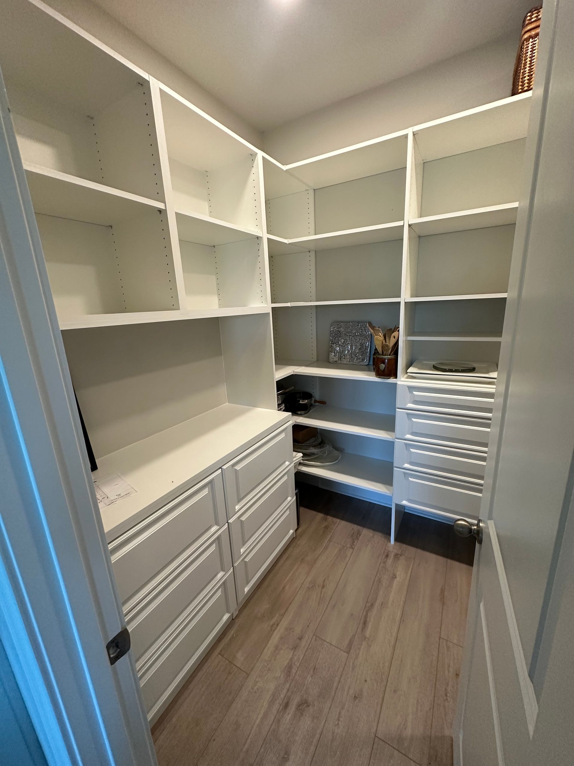 A walk in closet with lots of shelves and drawers.