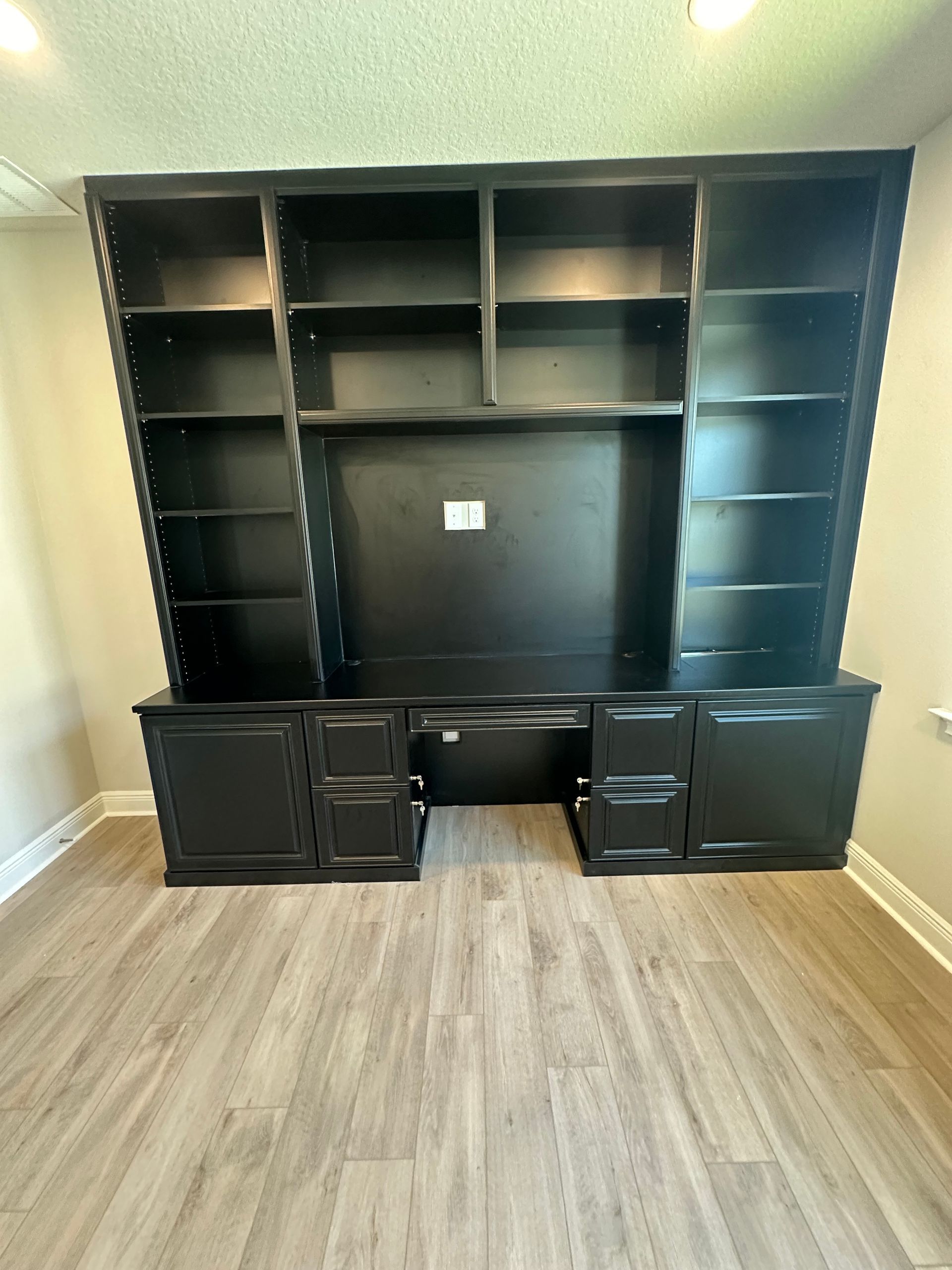 There is a large black bookshelf in the middle of the room.