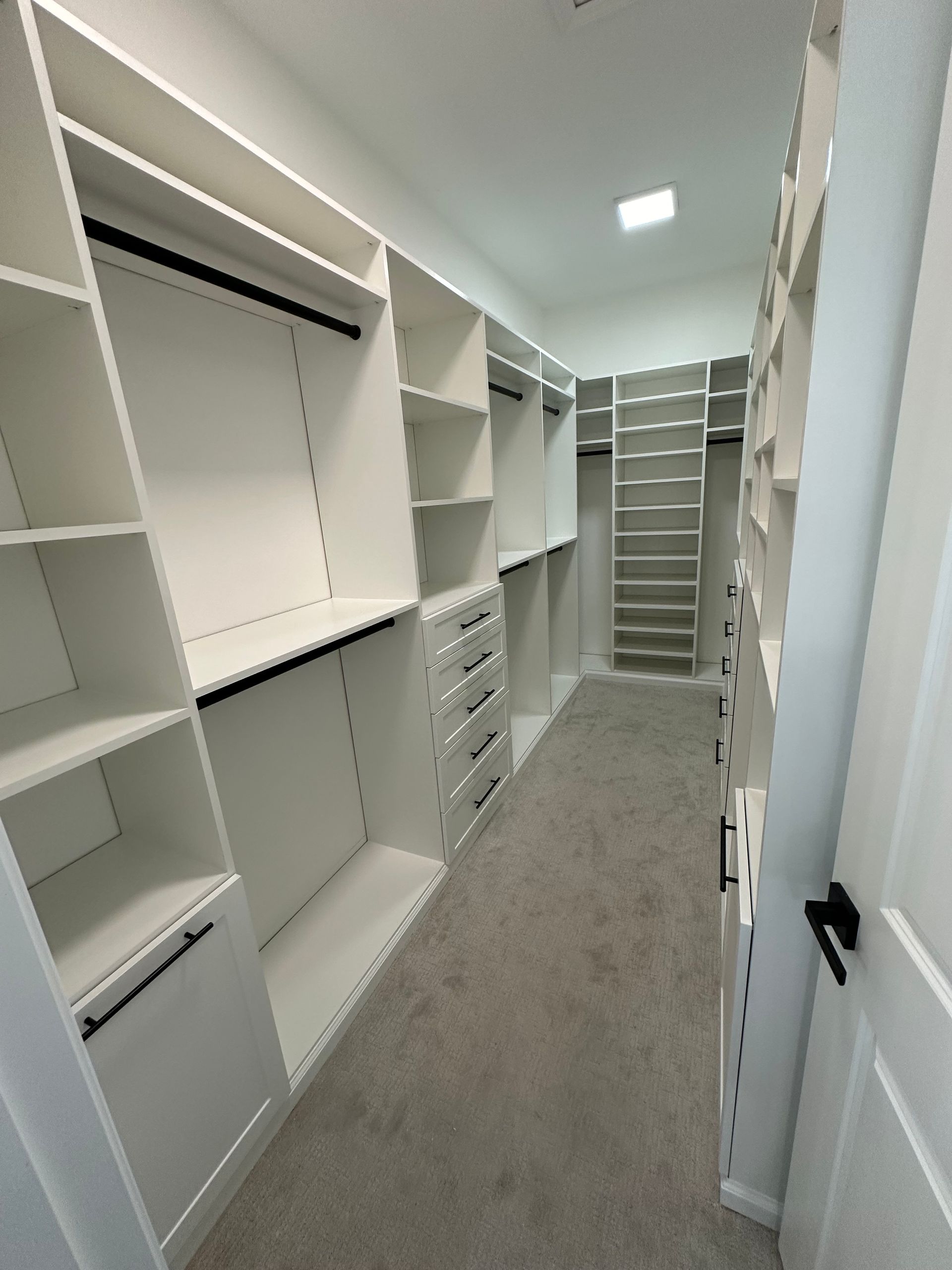A walk in closet with lots of shelves and drawers
