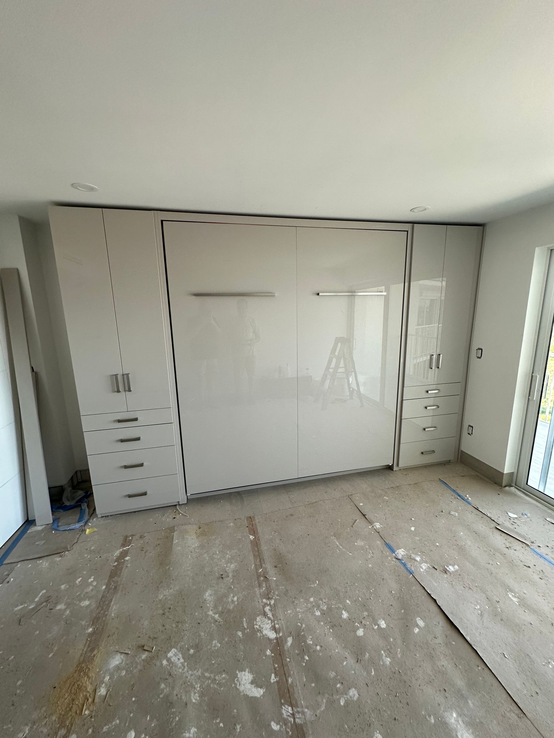 A room with a large white wall and a ladder in it.