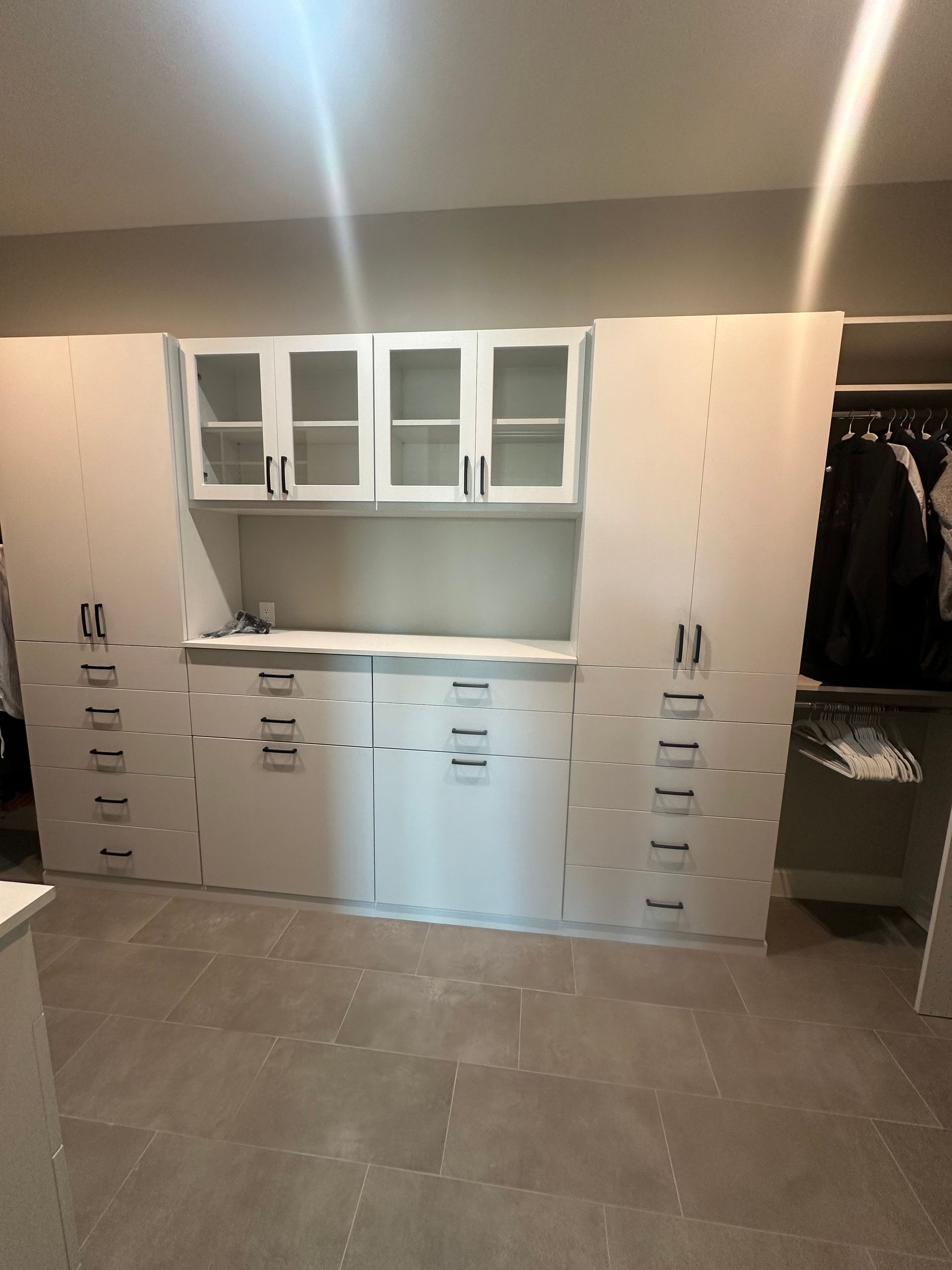 A closet with a lot of white cabinets and drawers