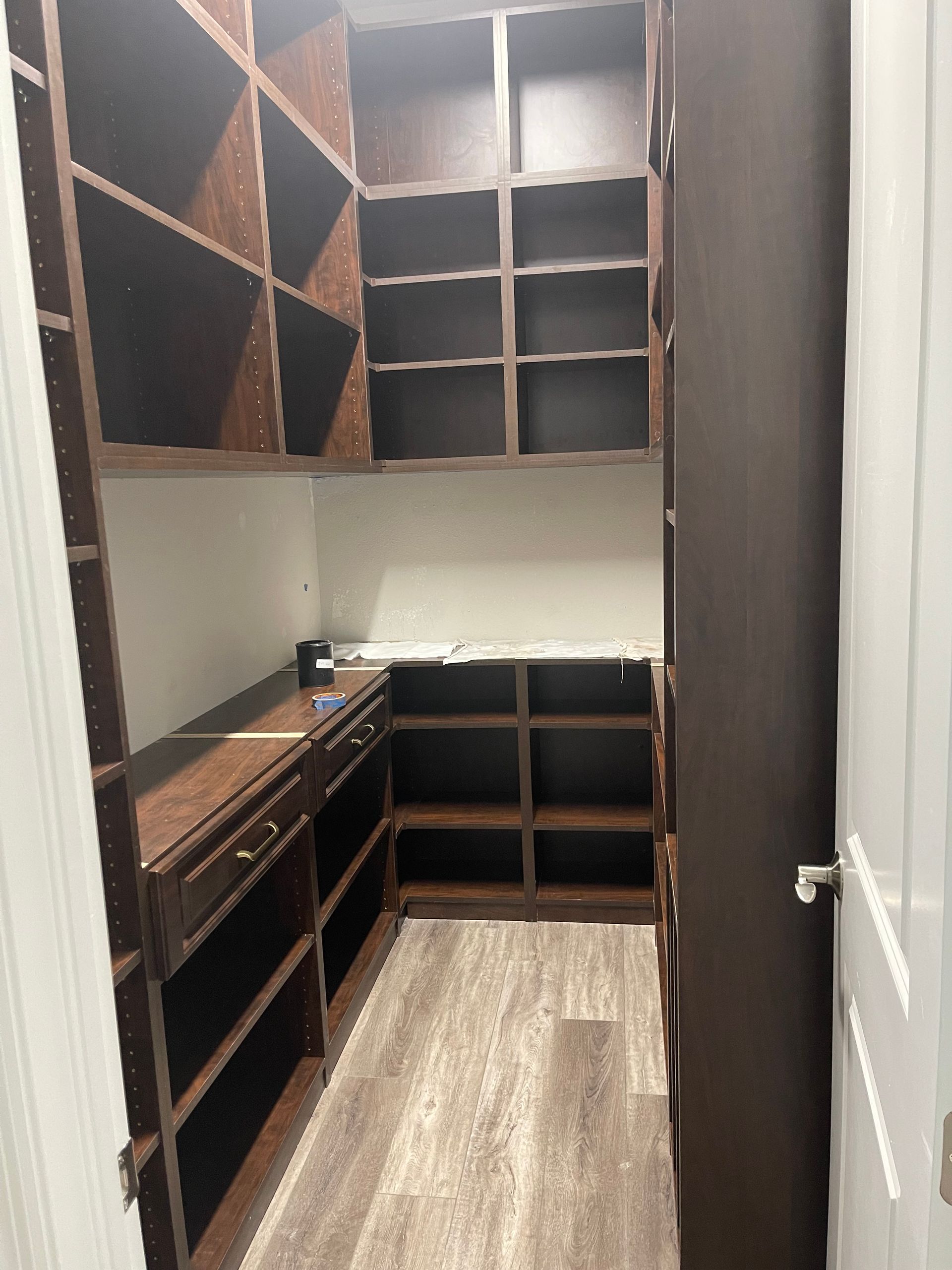 A walk in closet with lots of shelves and drawers.