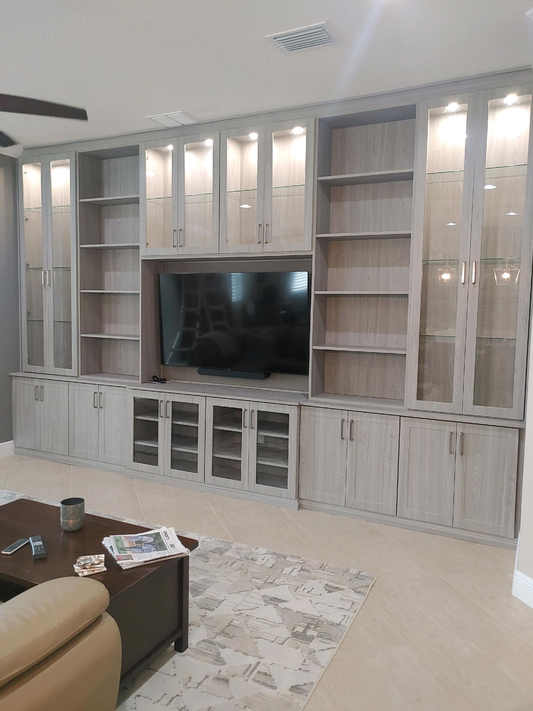 A living room with a large entertainment center and a flat screen tv.