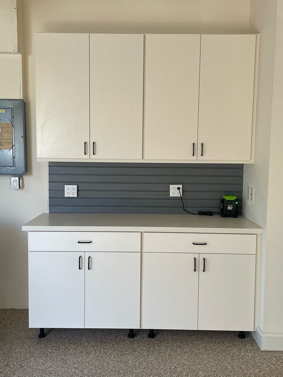 A kitchen with white cabinets and a gray wall.