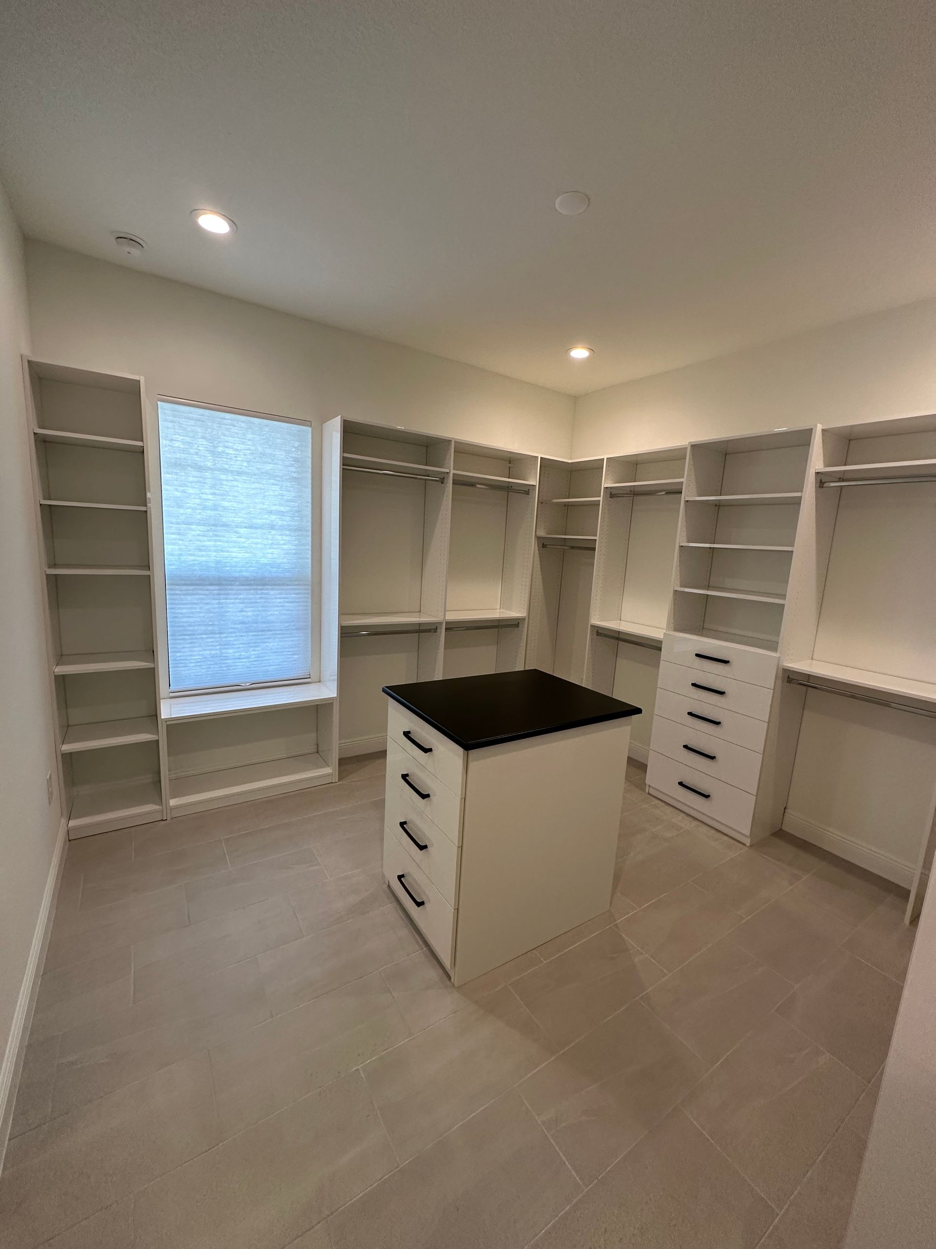 A walk in closet with lots of shelves and drawers and a window.