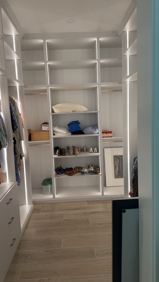 A walk in closet filled with lots of shelves and clothes.