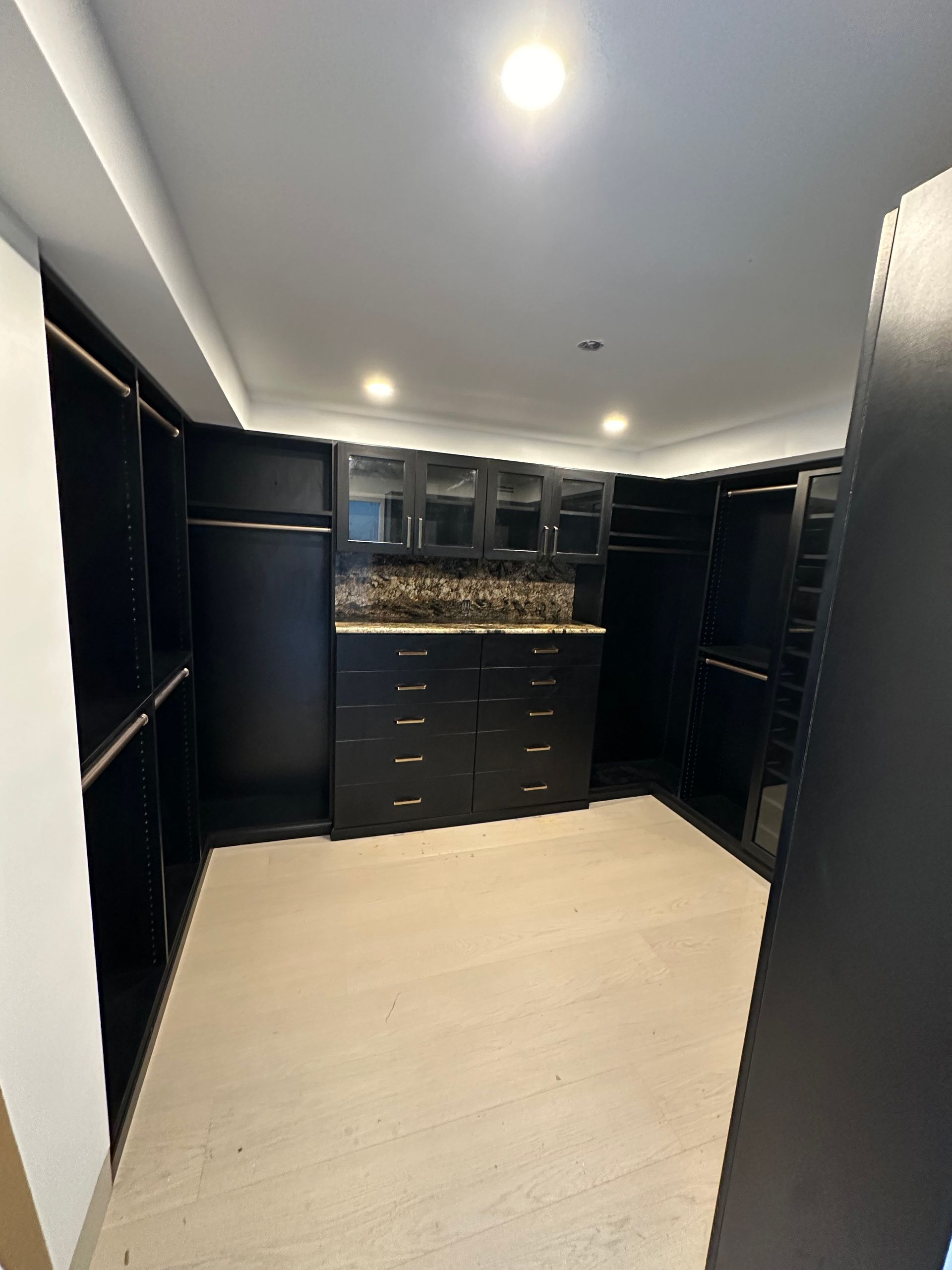 A large walk in closet with black cabinets and drawers