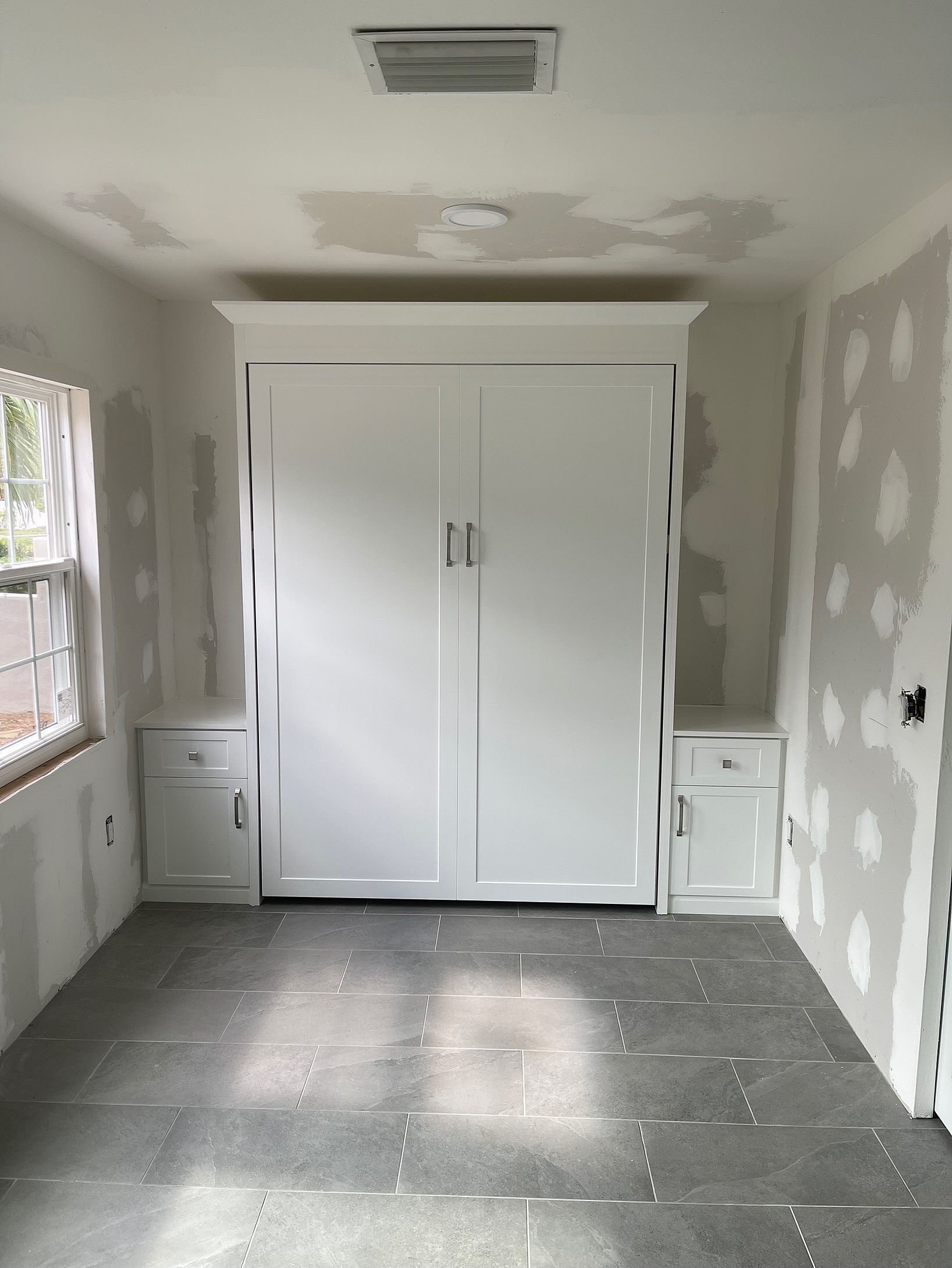 A room with a wall mounted bed and a window.