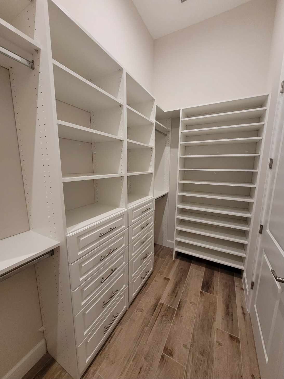 A walk in closet with lots of shelves and drawers.