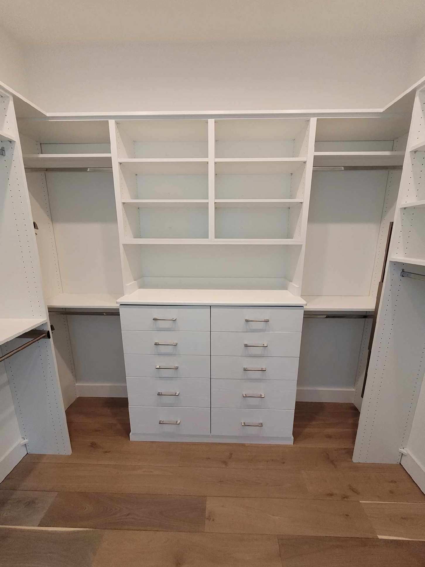 A walk in closet with lots of shelves and drawers.