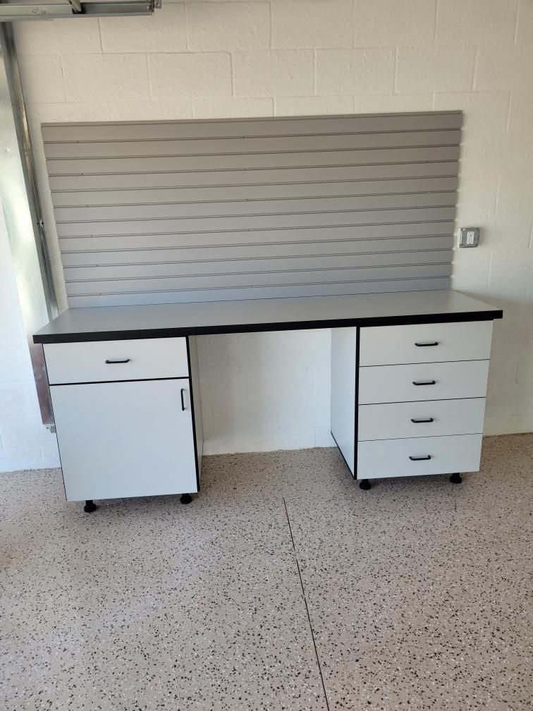 A desk with drawers and a cabinet in a garage.