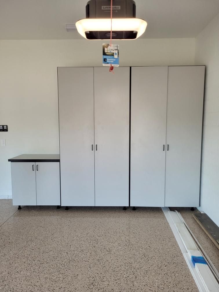A garage with white cabinets and a ceiling lift