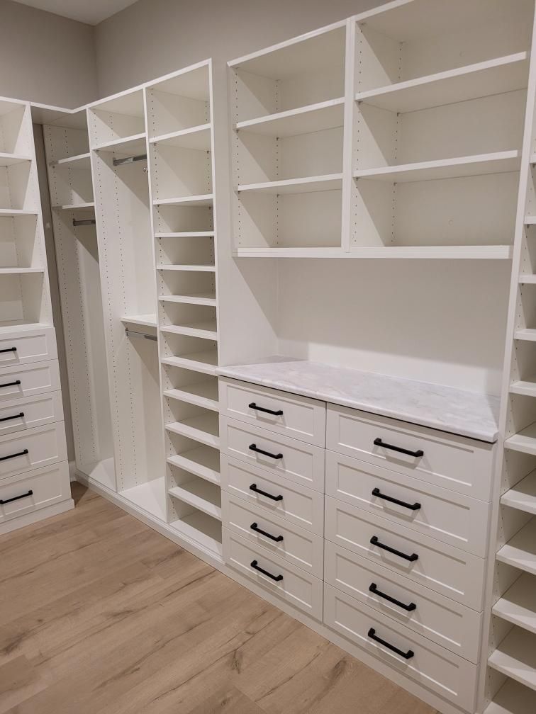 A walk in closet with lots of shelves and drawers.