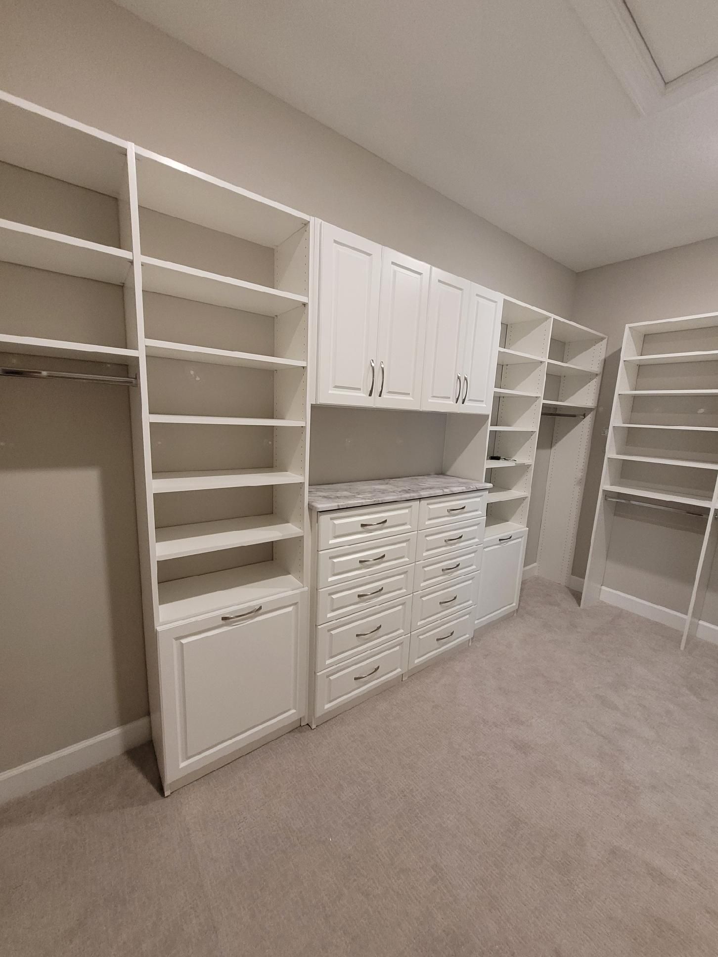 A walk in closet with lots of shelves and cabinets.